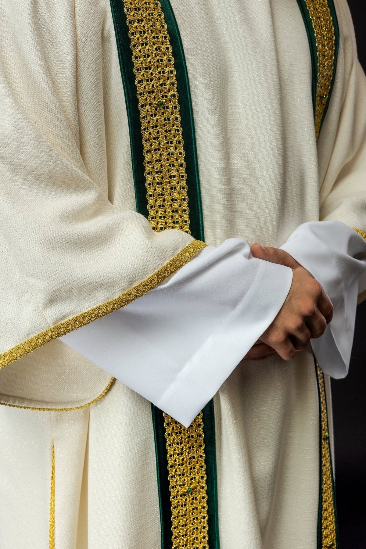 Handcrafted dalmatic close-up of gold-trimmed ivory sleeve and green orphrey