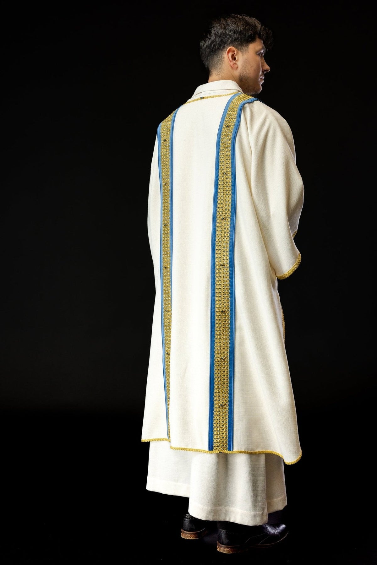 Handcrafted dalmatic three-quarter back view with white fabric and blue-and-gold orphrey