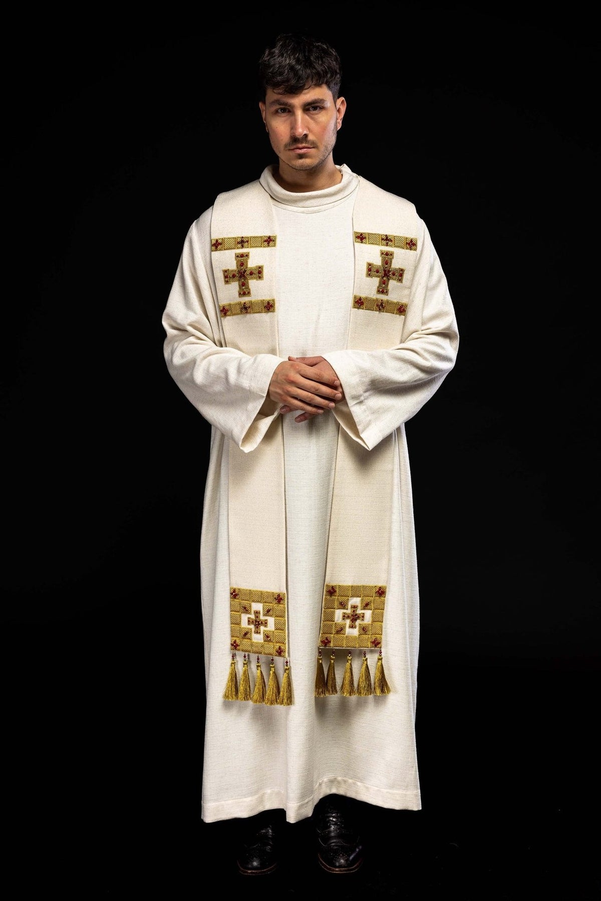 Stole worn in front view, showing white fabric, gold embroidery, stones and tassels