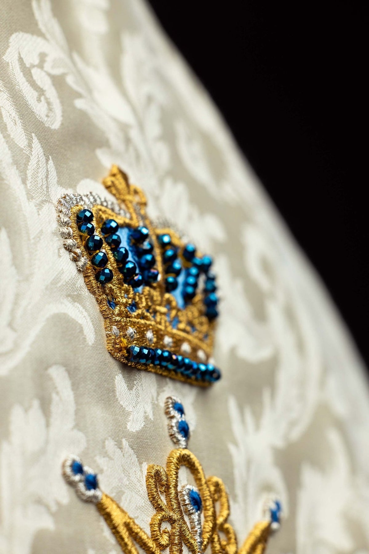 Handcrafted Marian cope close-up with blue natural stones and gold embroidery on ecru fabric