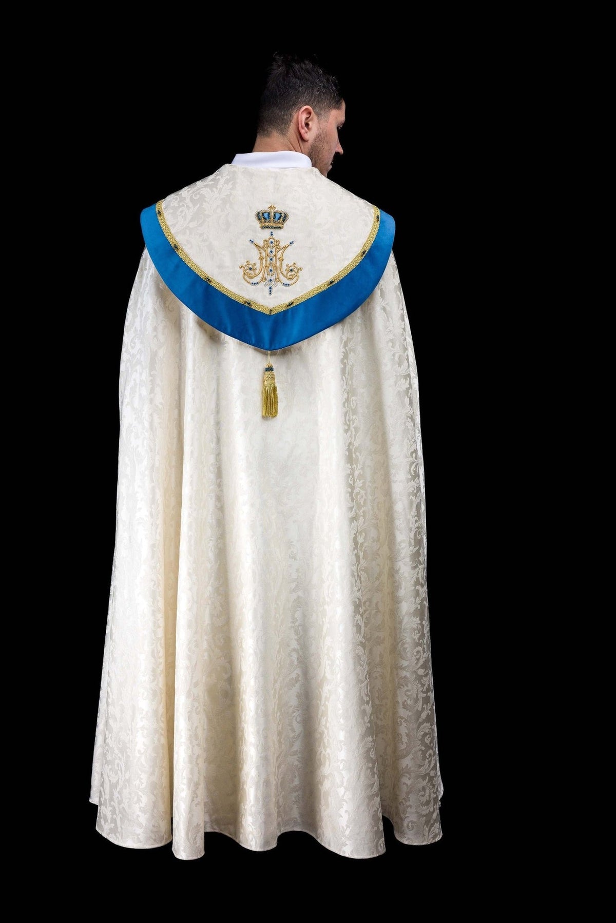 Marian cope back view in ecru jacquard fabric with blue velvet yoke and embroidered Marian symbol