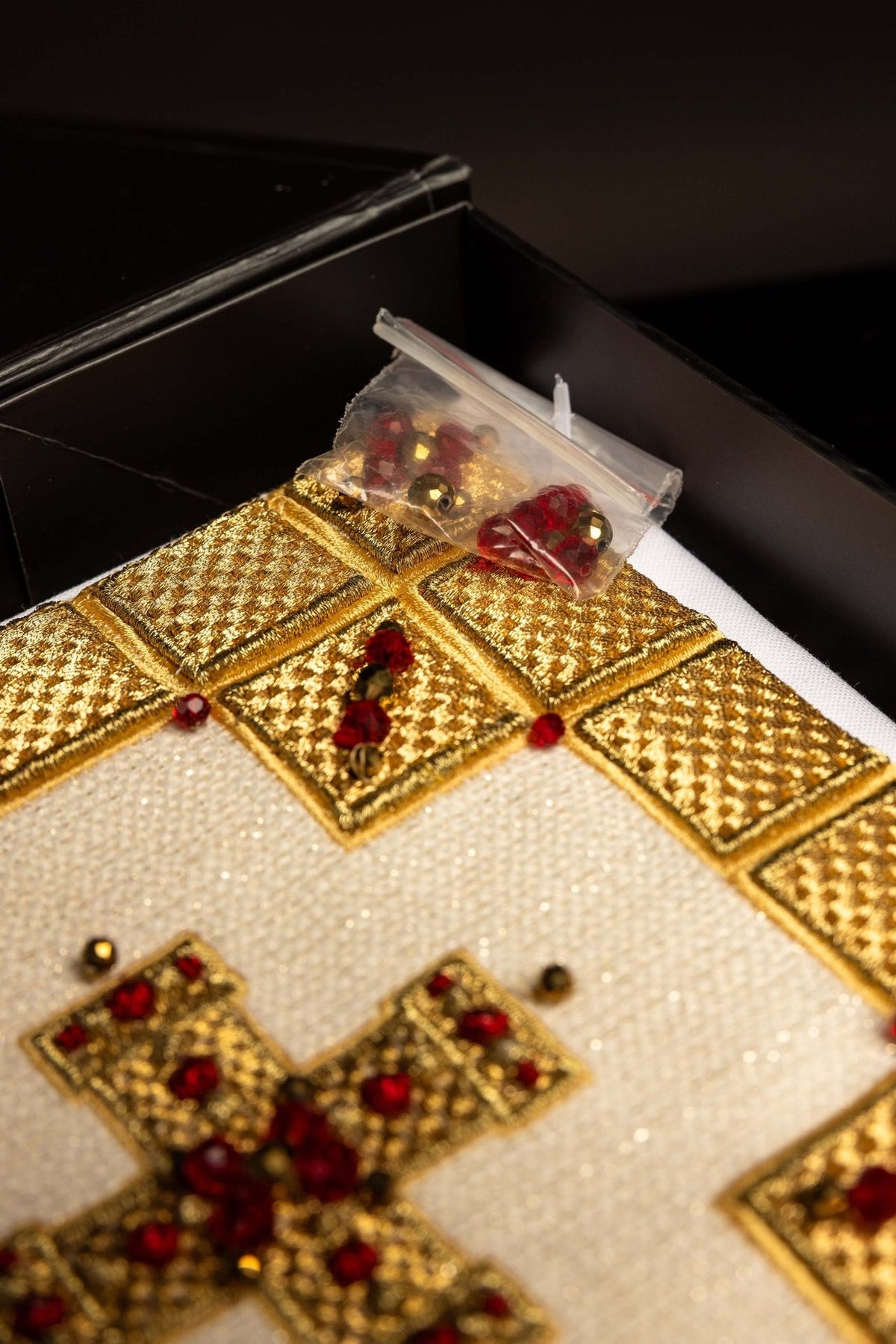 Altar linen set detail with gold embroidered squares, red stones and white fabric