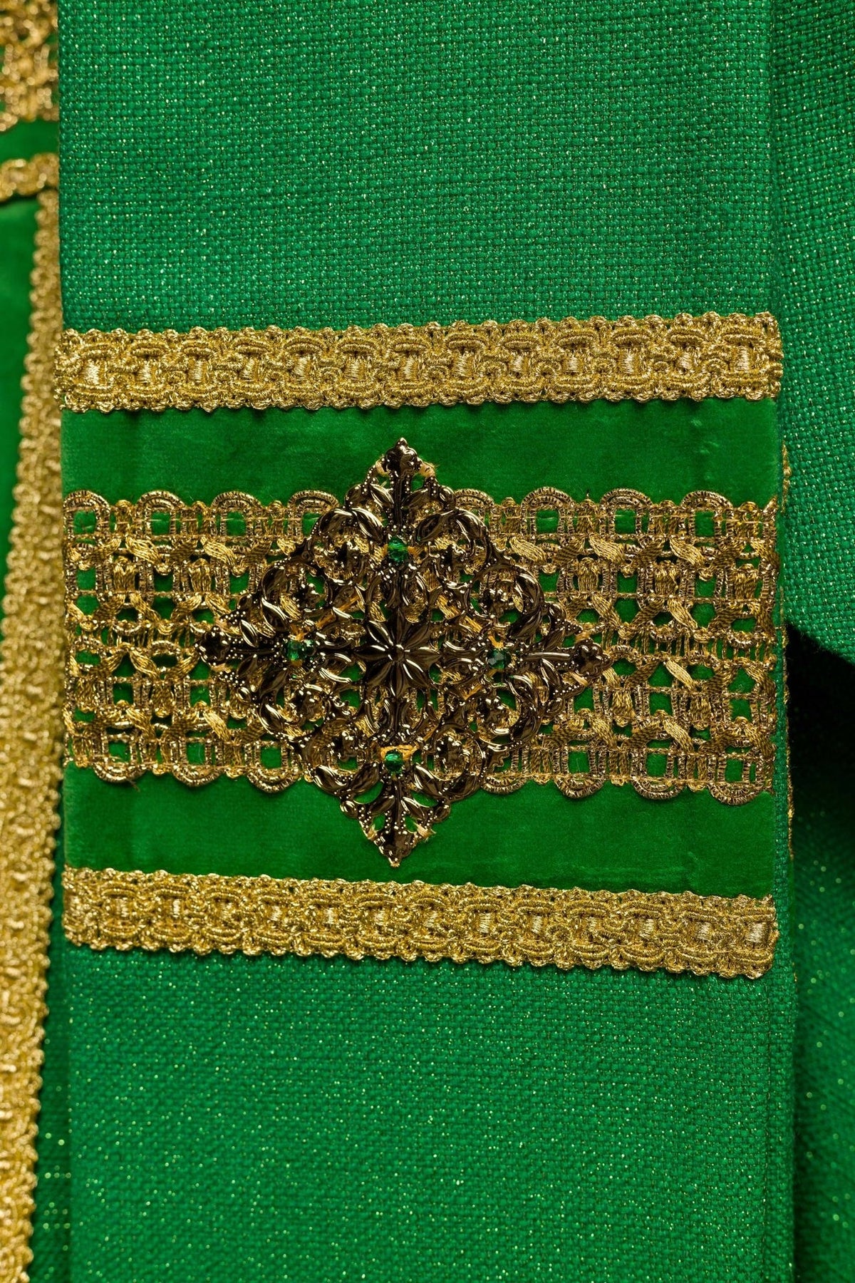 Green chasuble sleeve detail with a gold embroidered cross