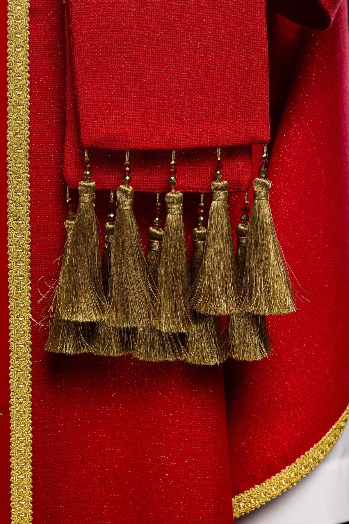 Red chasuble sleeve detail with hanging gold tassel and natural stones