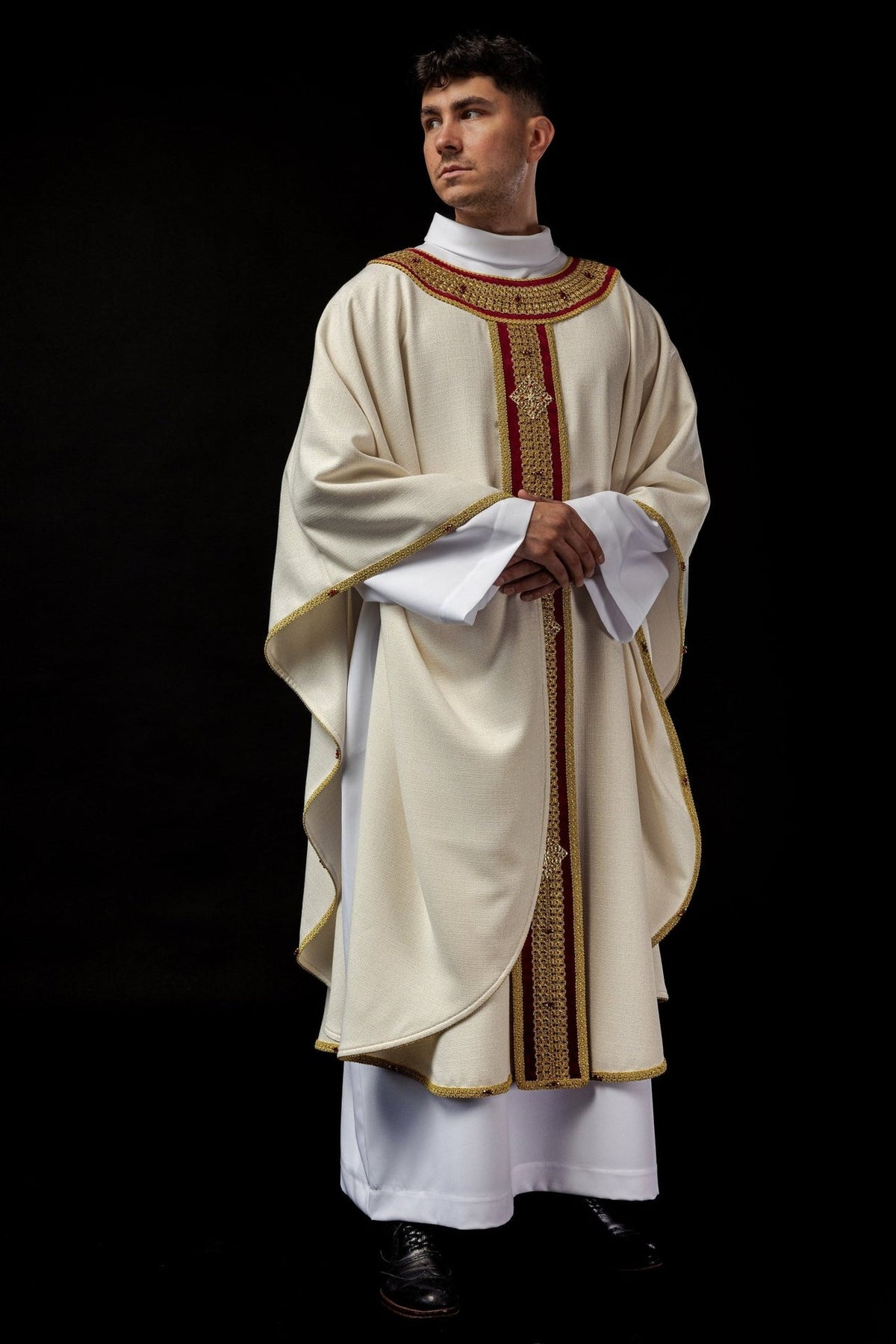Front view of the chasuble worn with its flowing ivory shape and gold trim