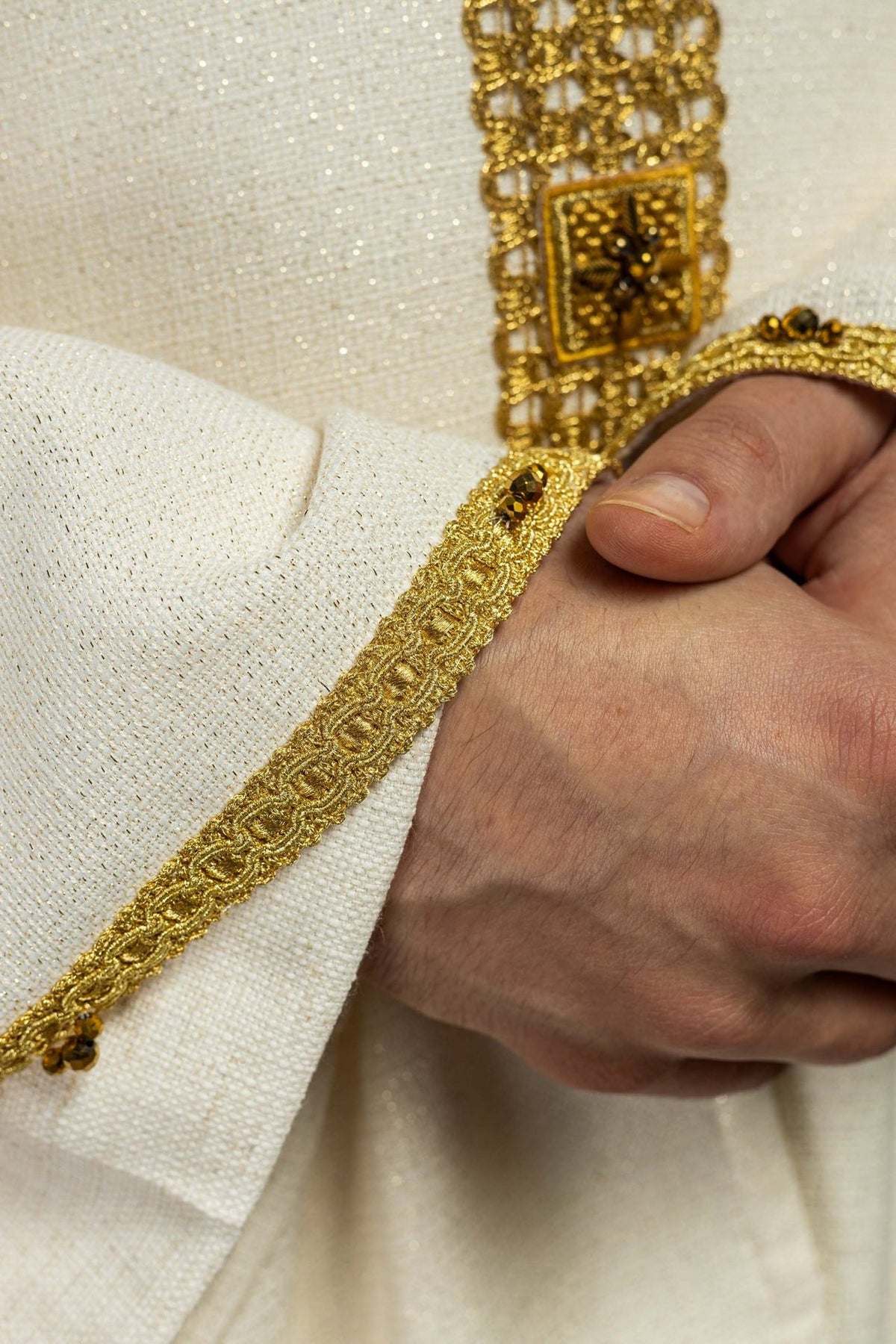 Ecru chasuble sleeve close-up with gold trim and natural stones
