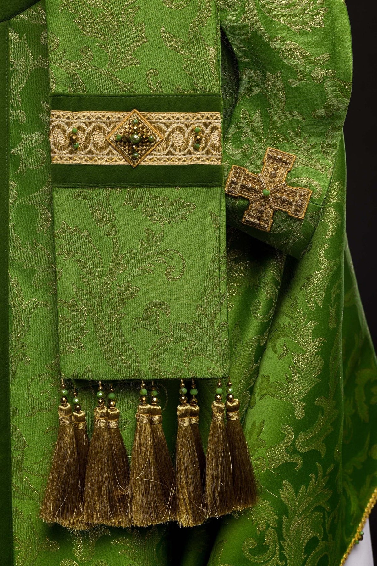 Green handcrafted chasuble detail with natural stones, cross and gold tassel
