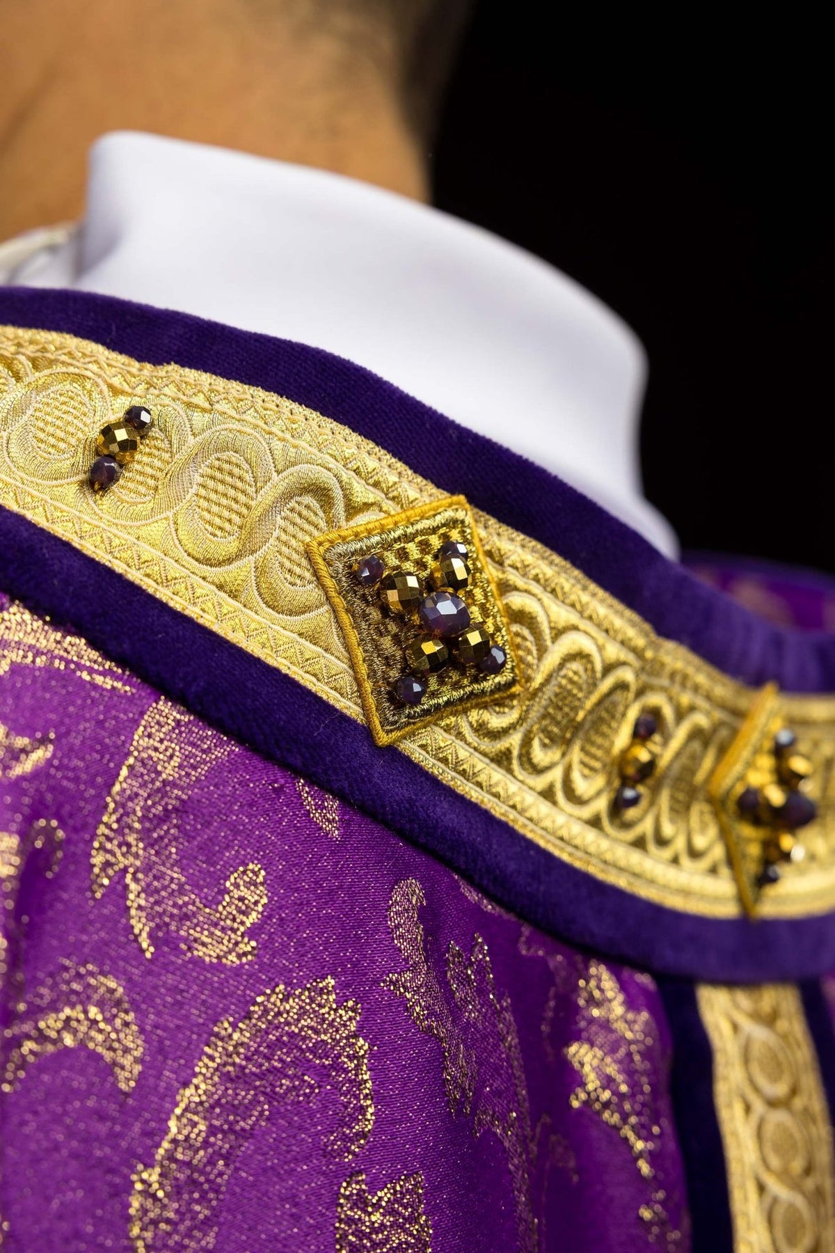 Purple chasuble detail with gold tassel trim, jeweled orphrey and cross embroidery