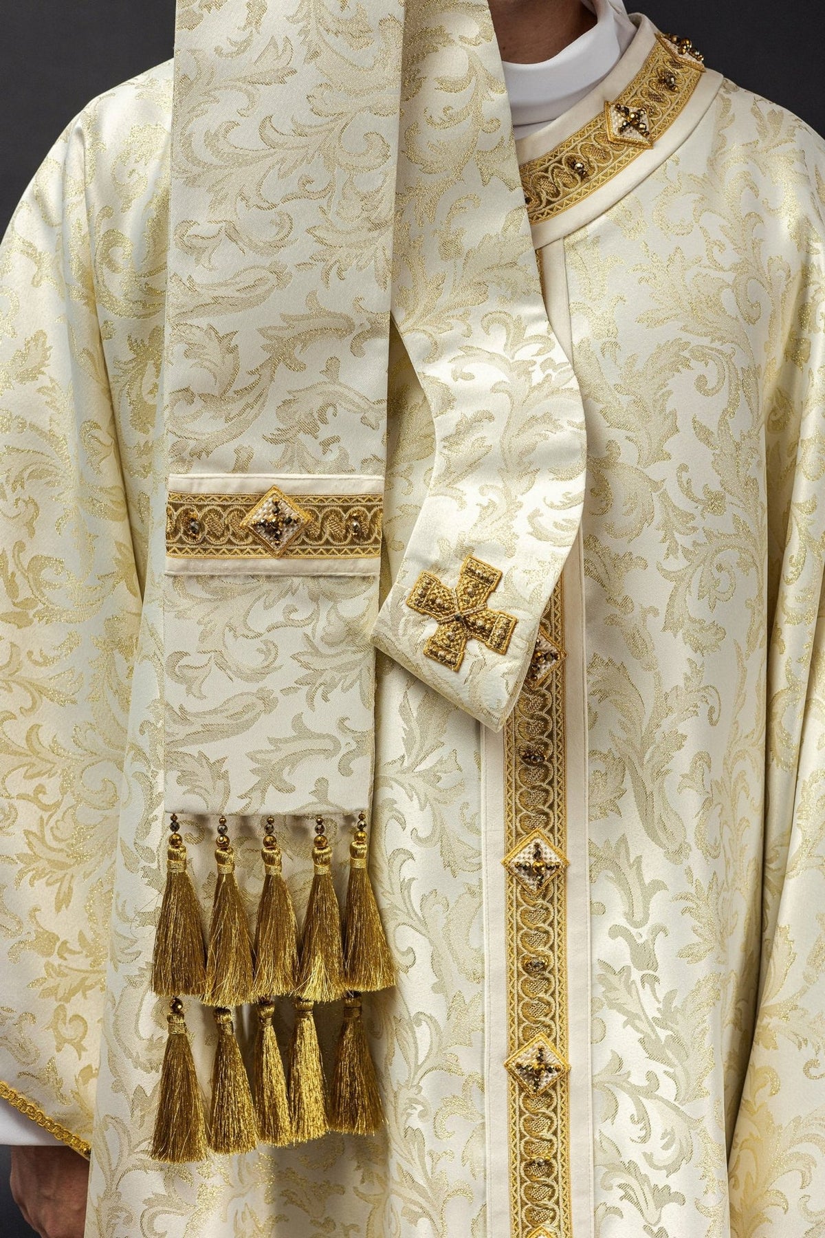 Chasuble sleeve close-up showing ecru fabric, gold trim and white lining