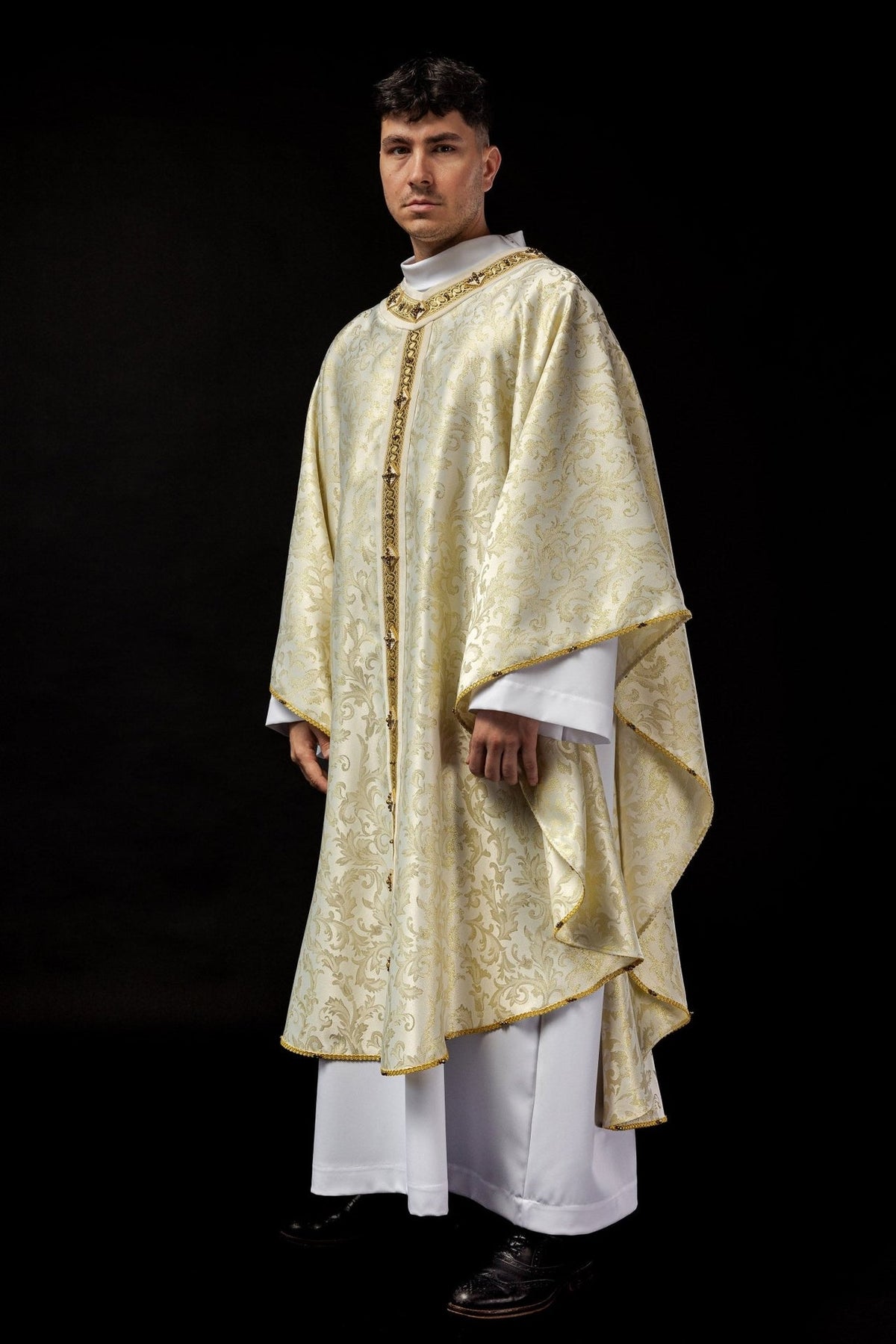 Chasuble three-quarter view showing flowing ecru fabric, gold trim and embroidered orphrey