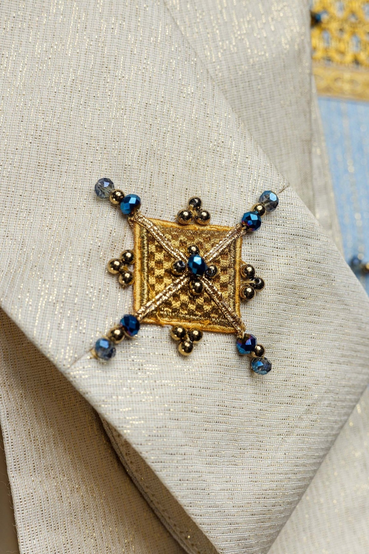 Marian chasuble, close-up of ivory fabric with gold square embroidery and blue stones