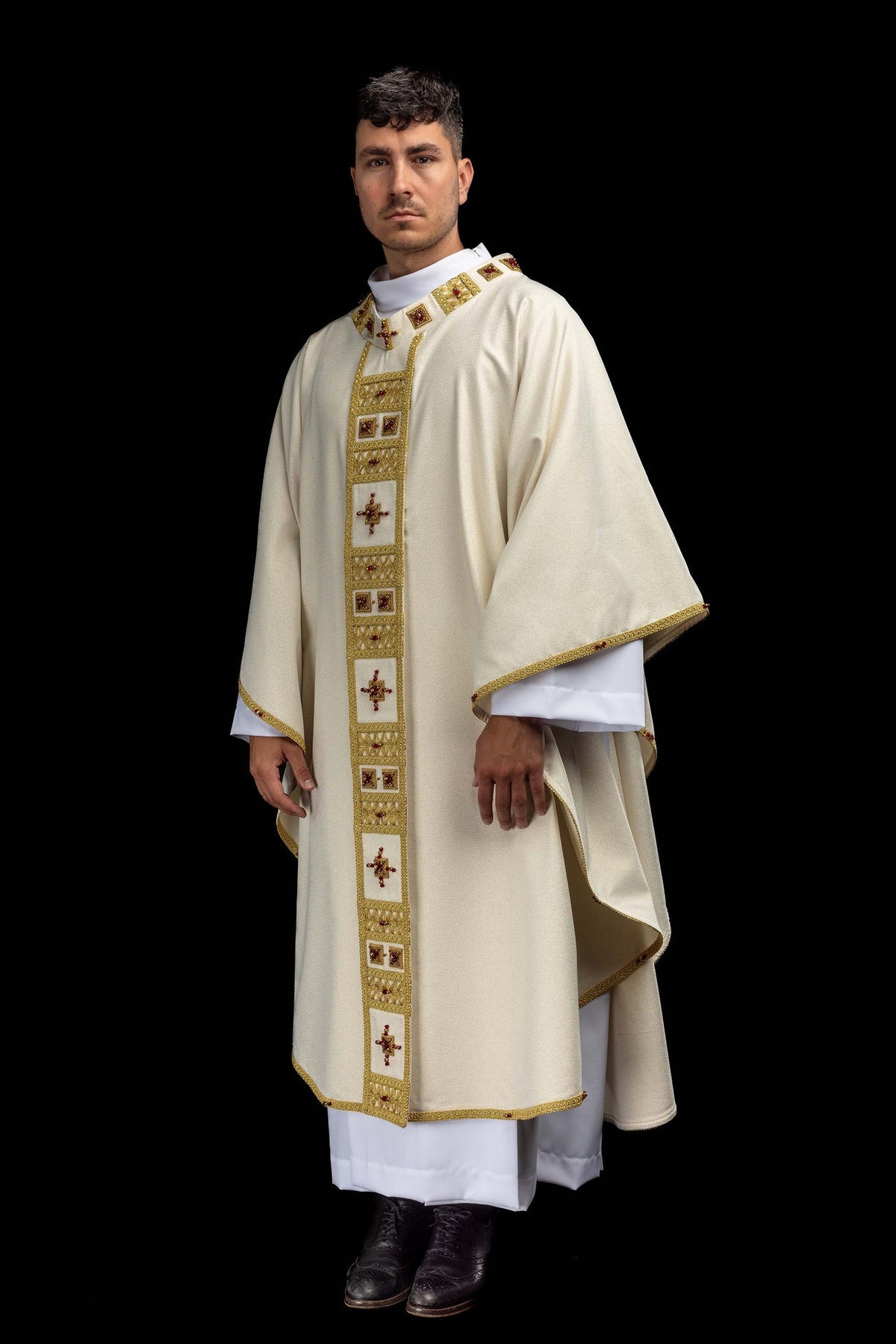 Handcrafted chasuble worn in a three-quarter front view with ivory fabric, gold trim, and red stone details