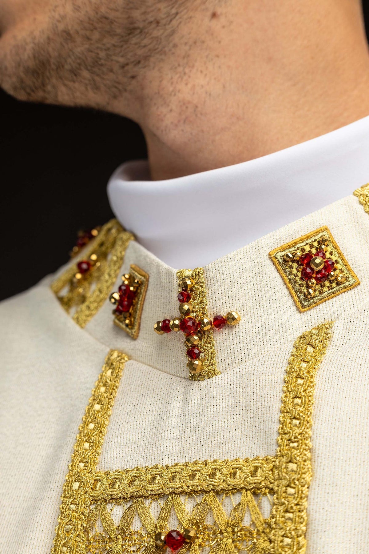 Handcrafted chasuble collar close-up with gold embroidery, red and gold stones, and a cross motif