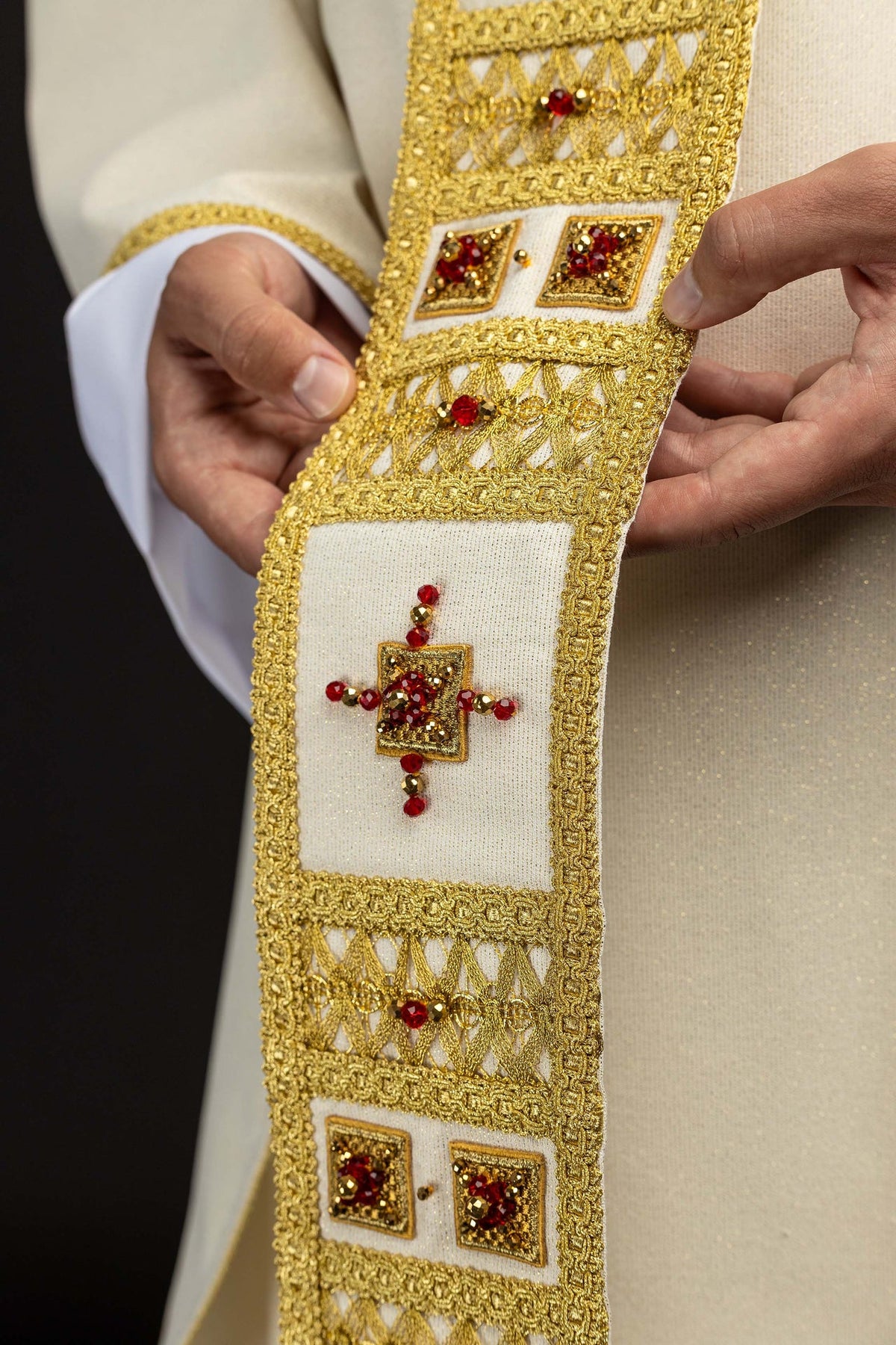 Handcrafted chasuble detail showing two square red and gold stone motifs in gold trim