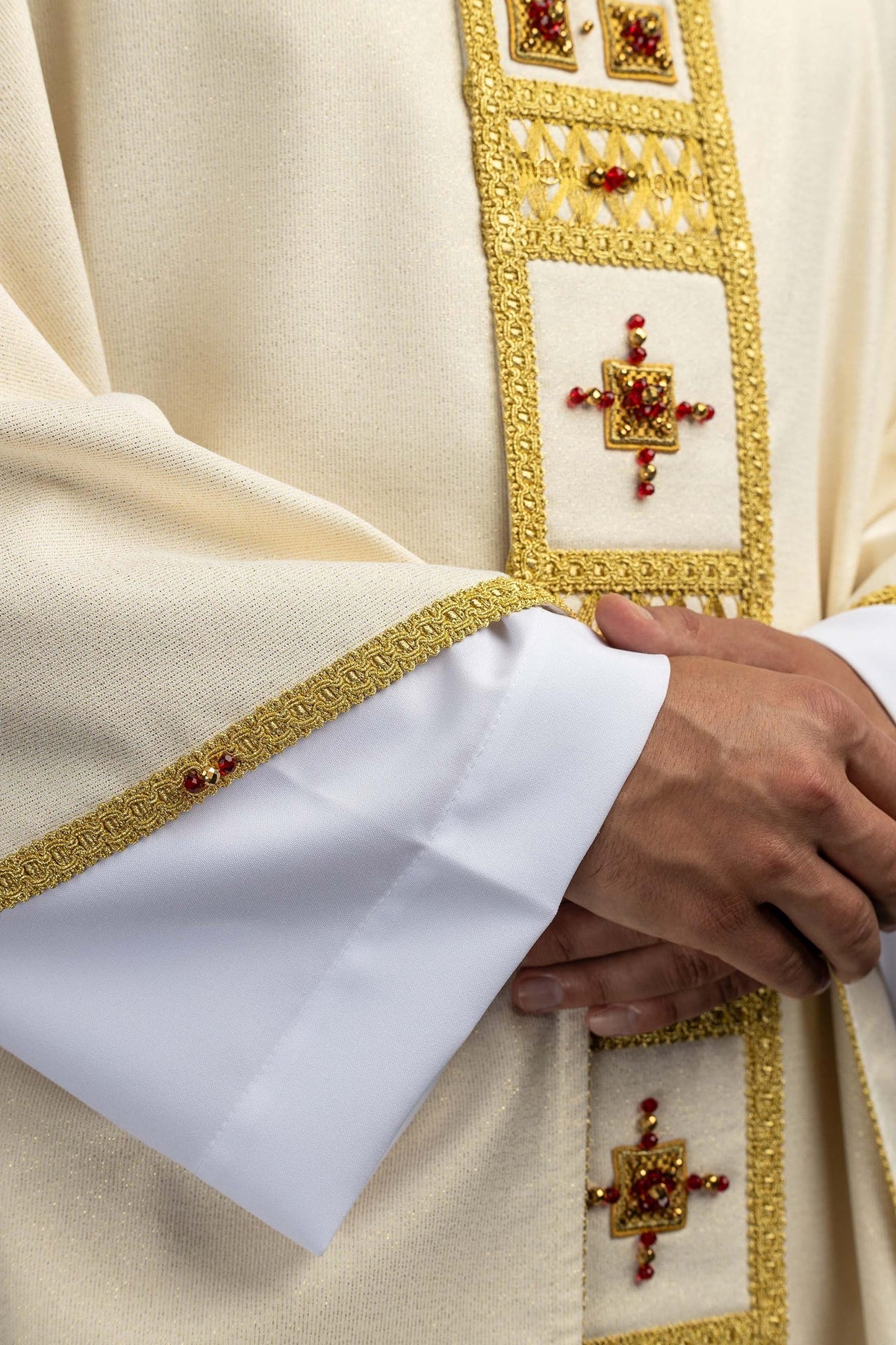 Handcrafted chasuble close-up of a red and gold beaded cross on the ivory front panel