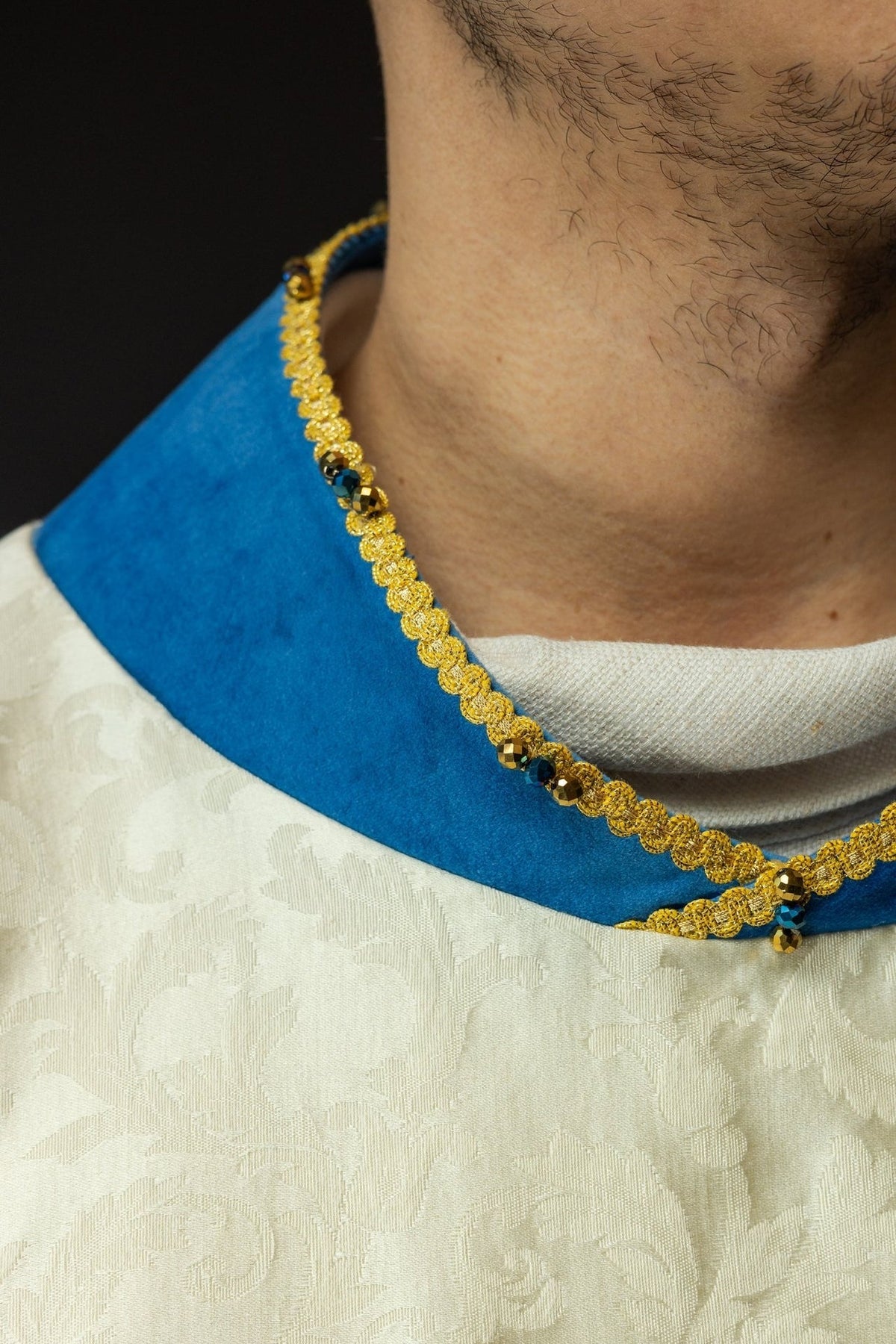 Marian chasuble close-up showing blue velvet collar with gold trim and natural stones