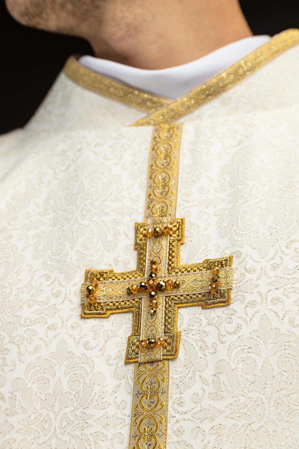 Chasuble close-up showing gold-trimmed collar, central band, and jeweled cross