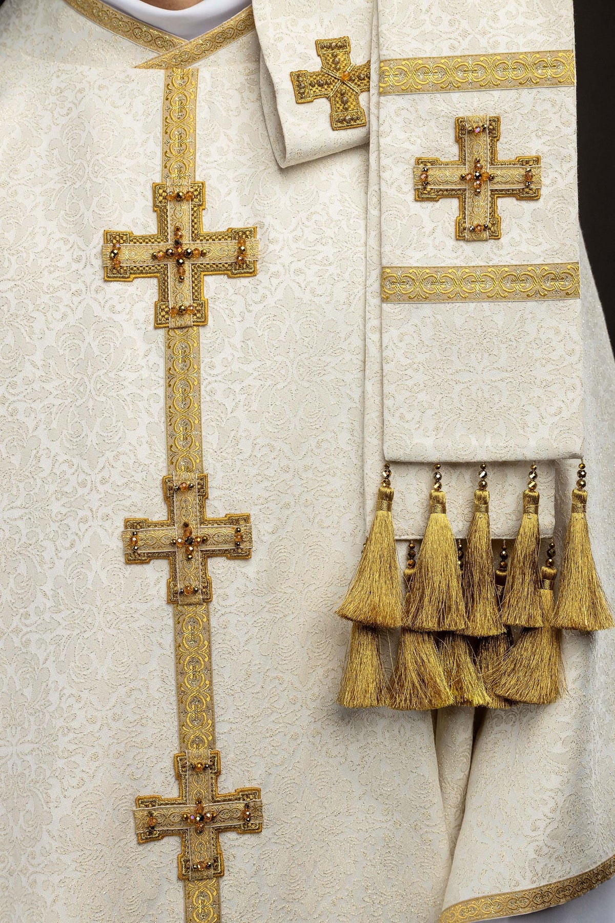 Chasuble detail with gold embroidered bands, jeweled crosses, and hanging gold tassels
