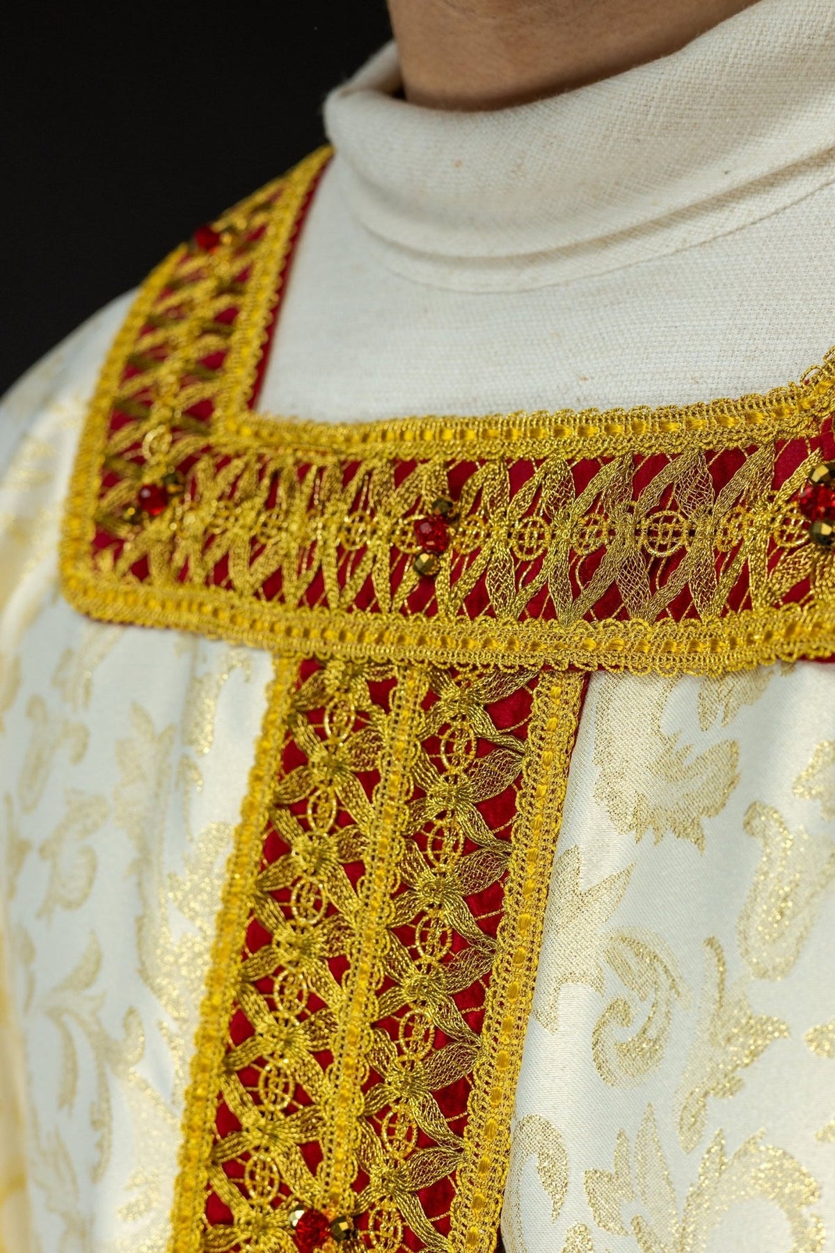 Handcrafted chasuble collar close-up with red velvet, gold embroidery and natural stones