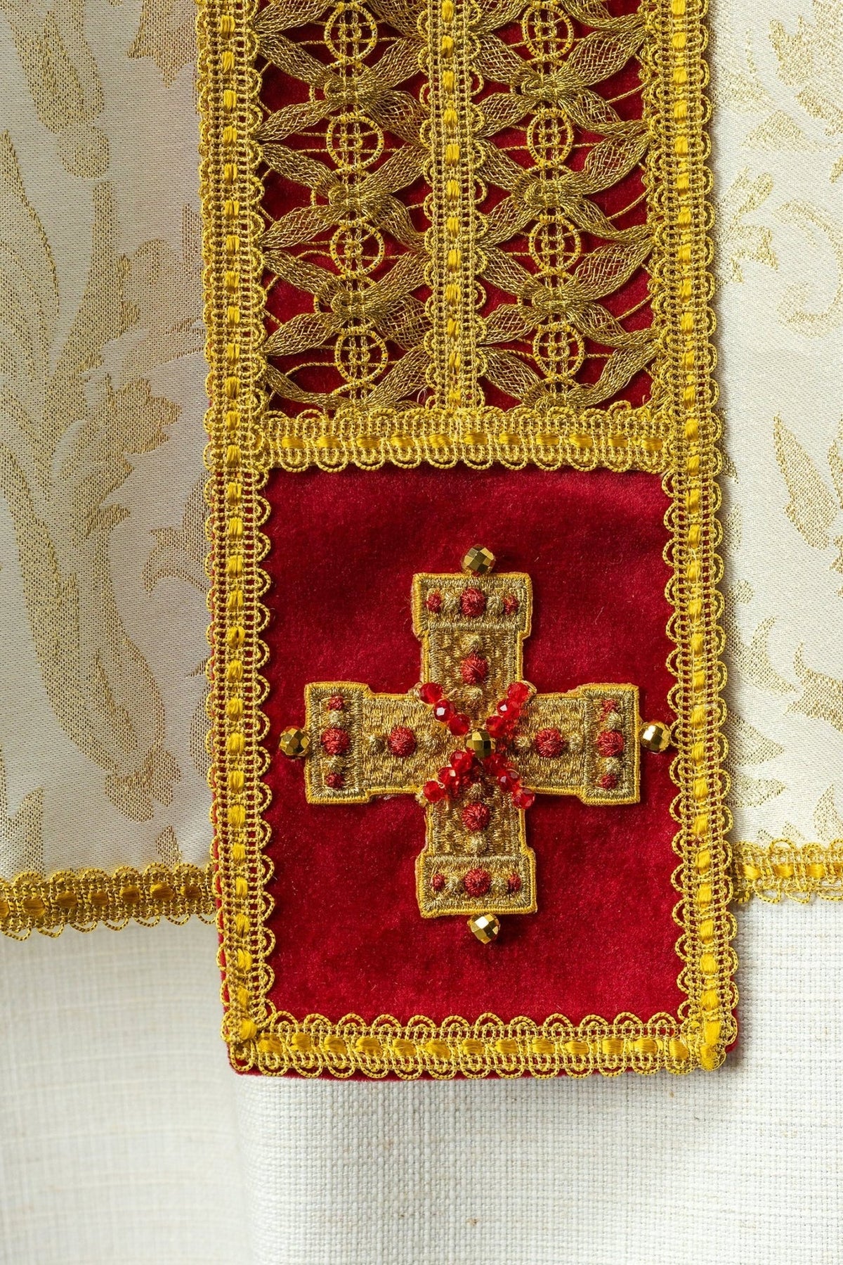 Handcrafted chasuble detail with red velvet panel, gold cross and natural stones