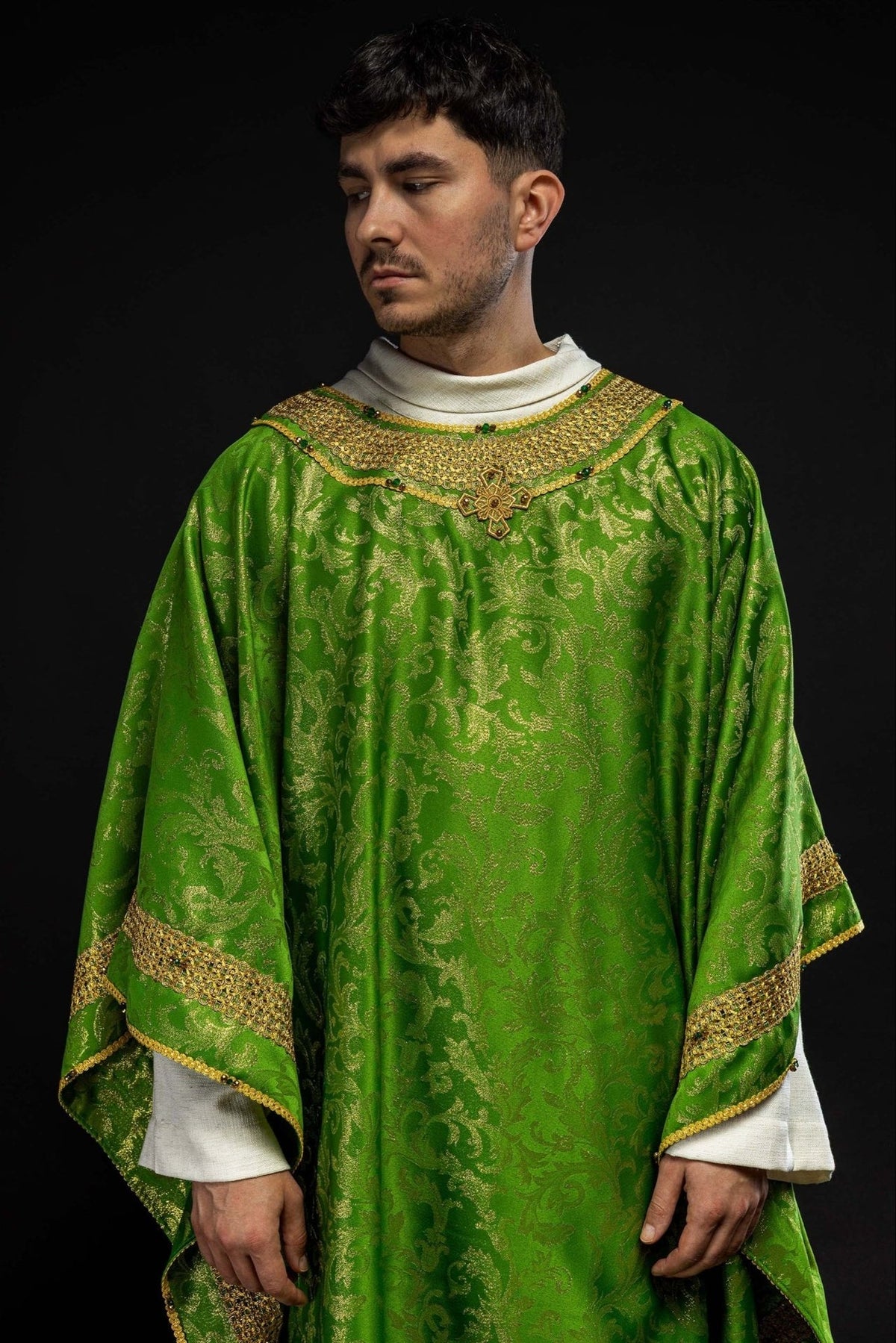 Green chasuble worn in a close front view with gold embroidery and natural stones