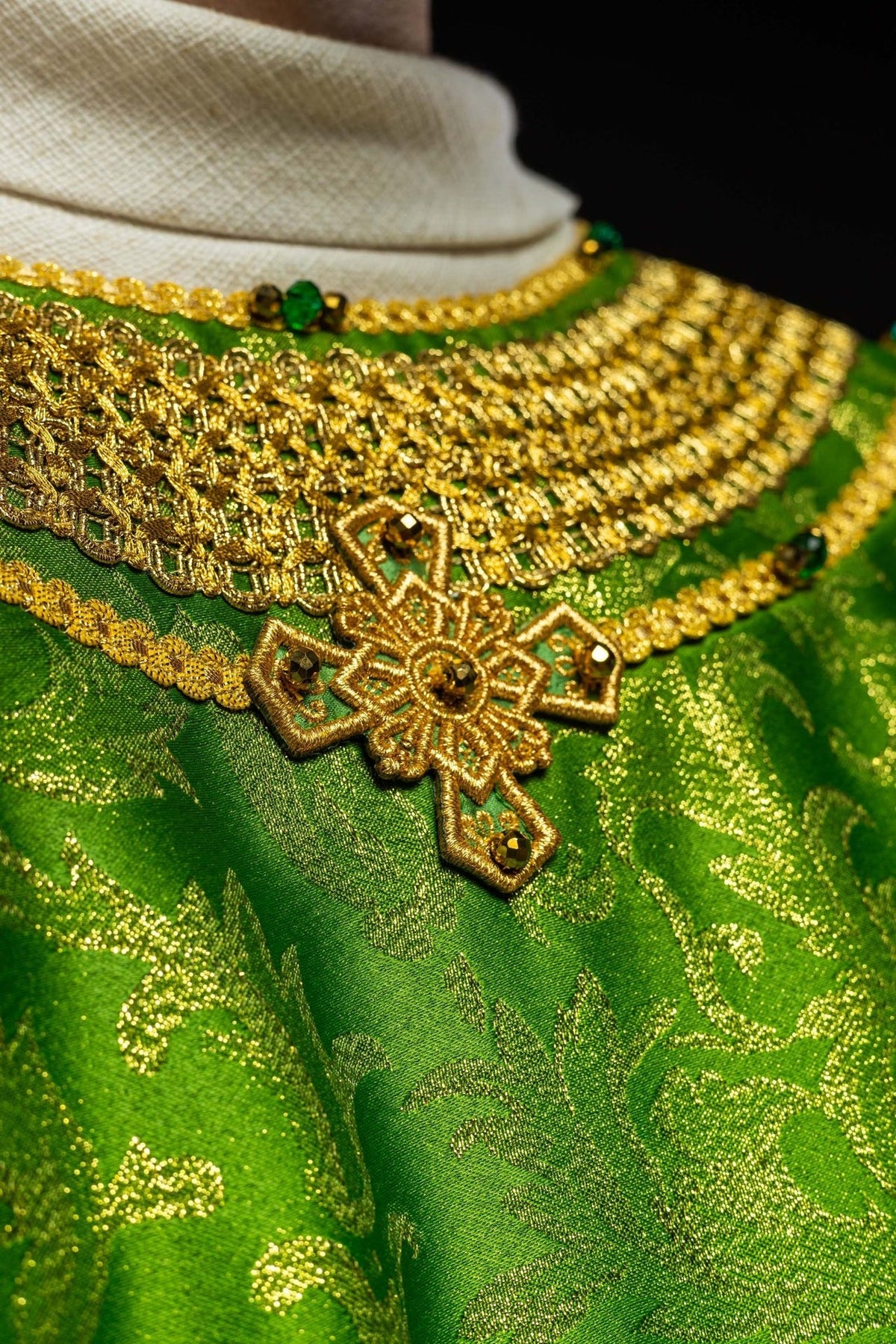 Green chasuble neckline close-up with gold embroidery and cross detail