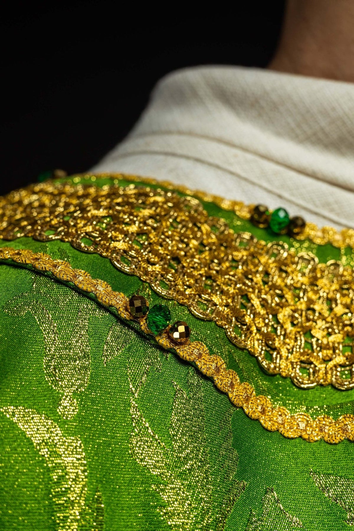 Green chasuble close-up showing gold cross, embroidery and green stones