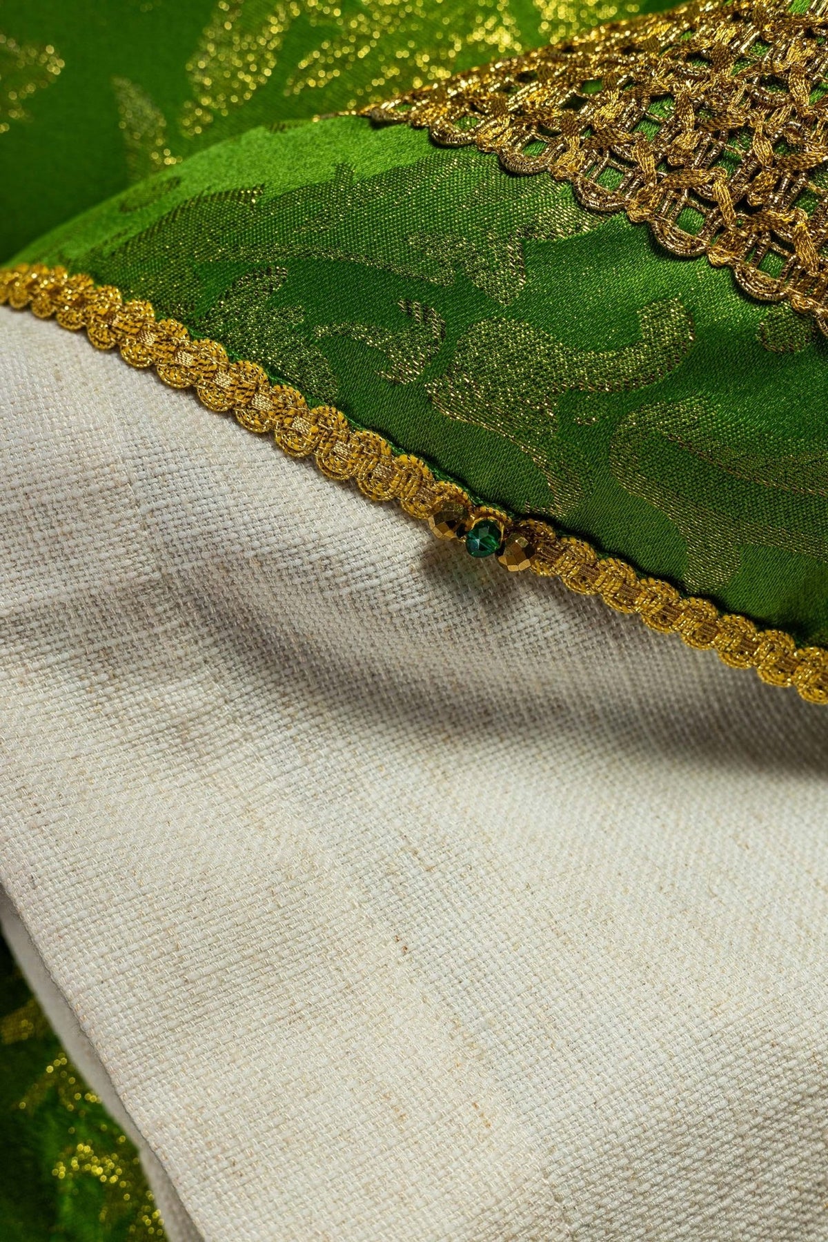 Green chasuble sleeve close-up with gold embroidery and patterned fabric