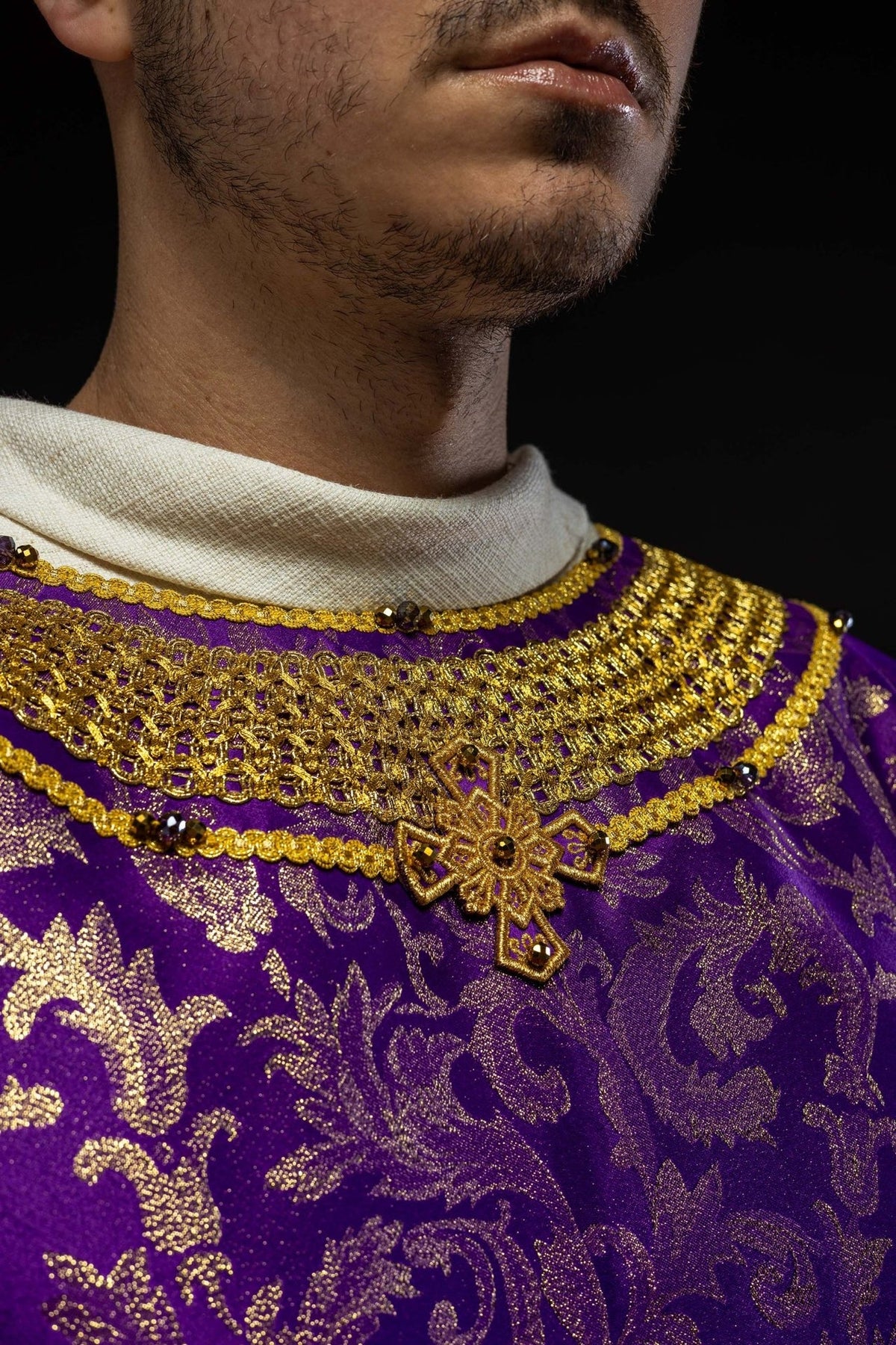 Purple chasuble neckline close-up with gold embroidery, cross and natural stones