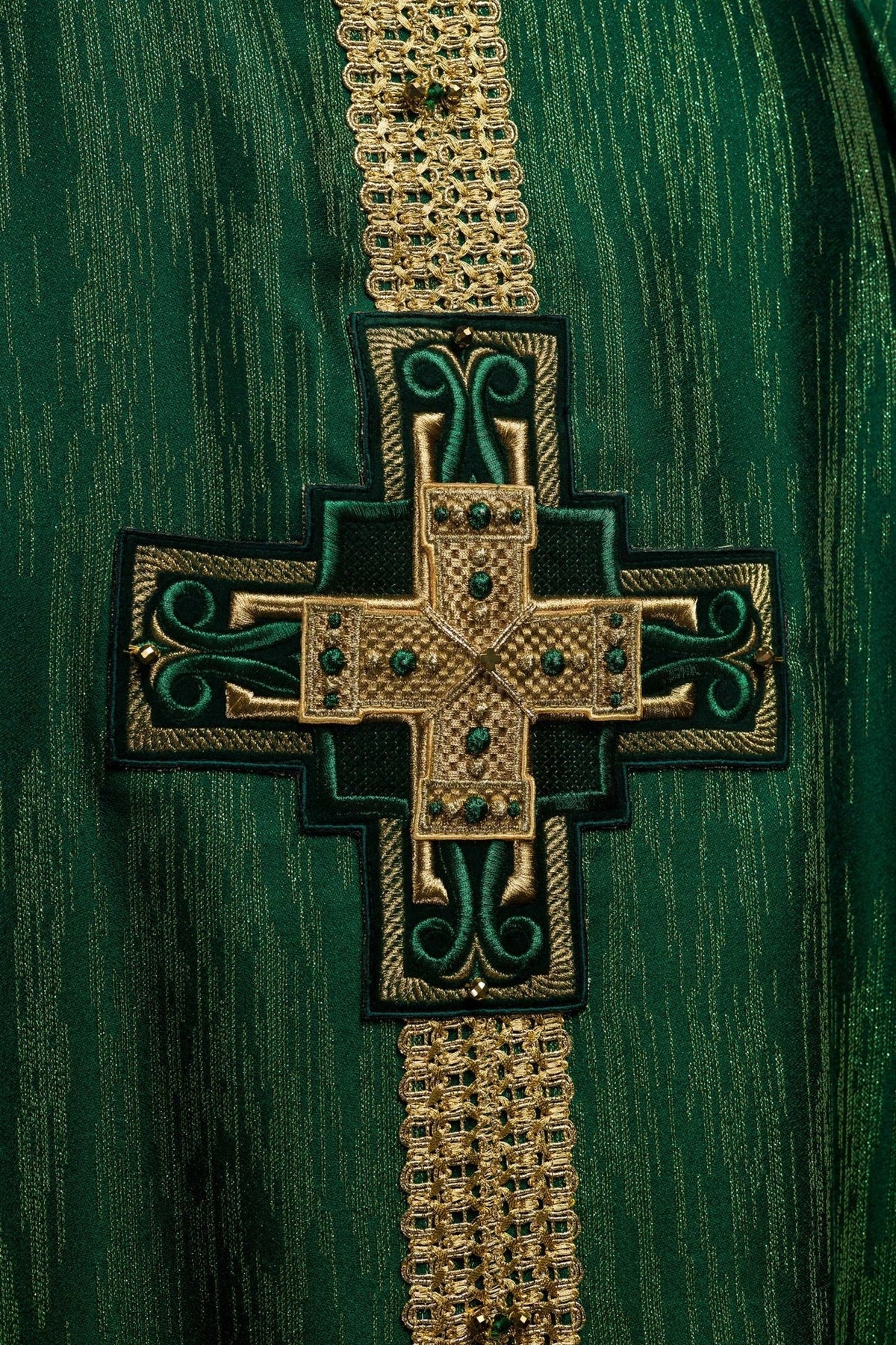 Green chasuble close-up showing gold cross embroidery and natural stones
