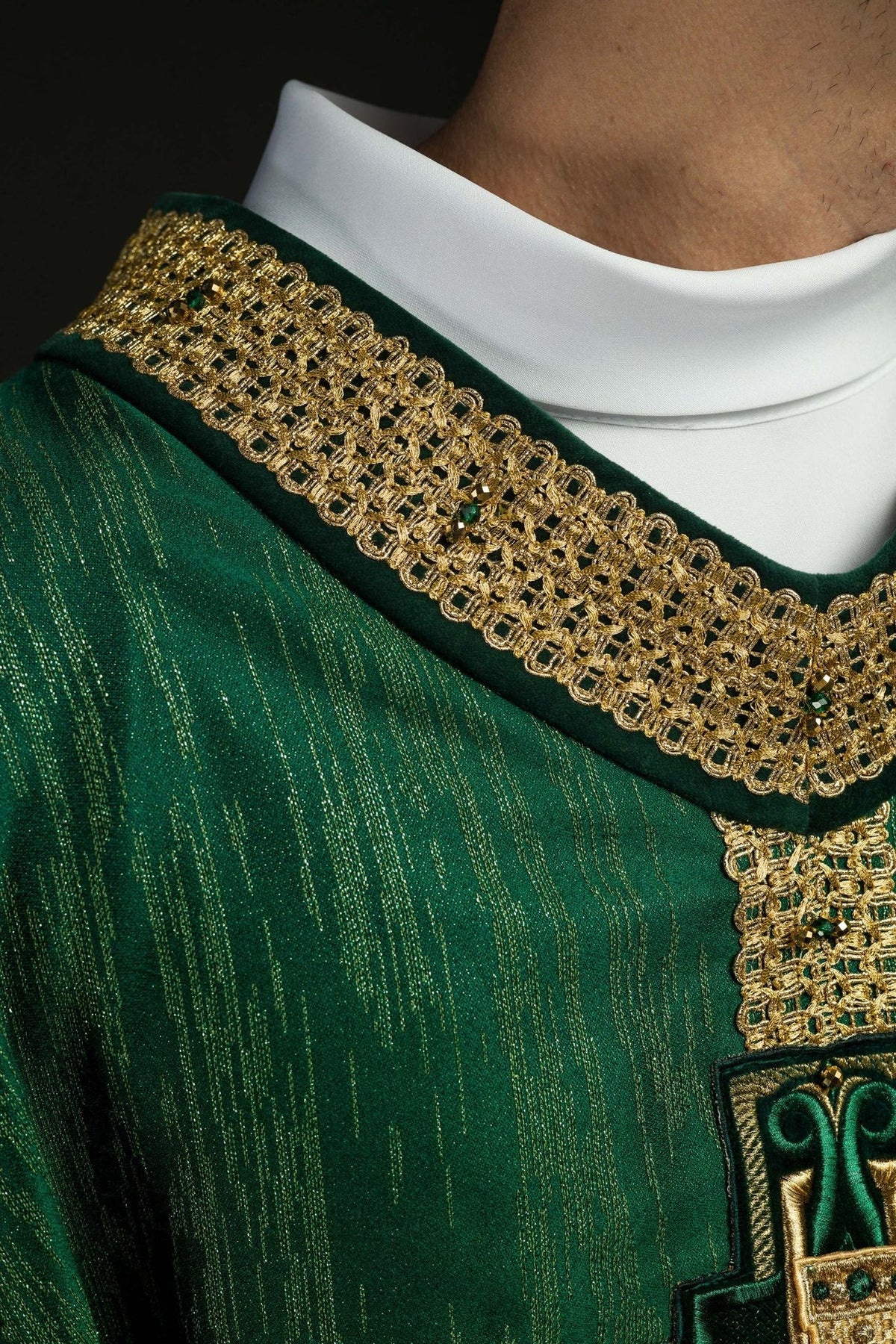 Green chasuble close-up showing gold sleeve trim and natural stones
