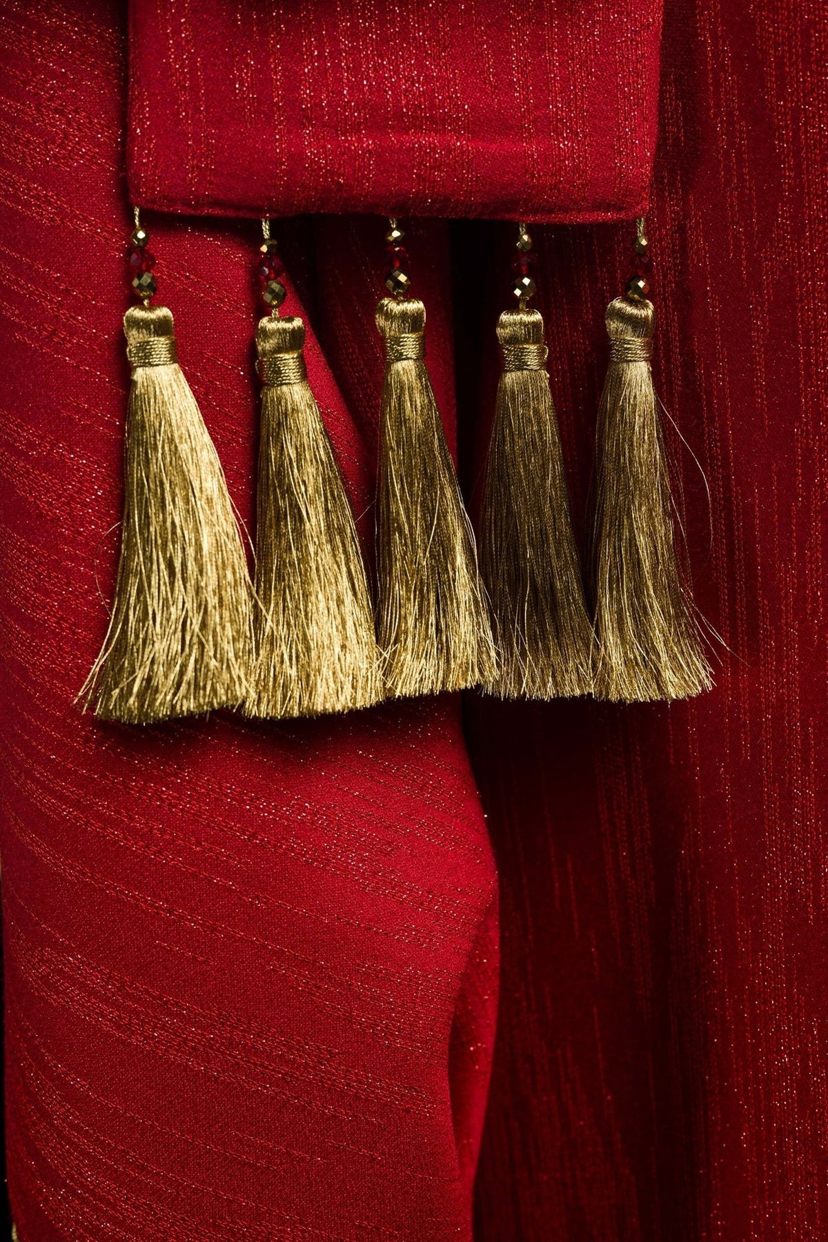 Red chasuble close-up of five gold tassel details