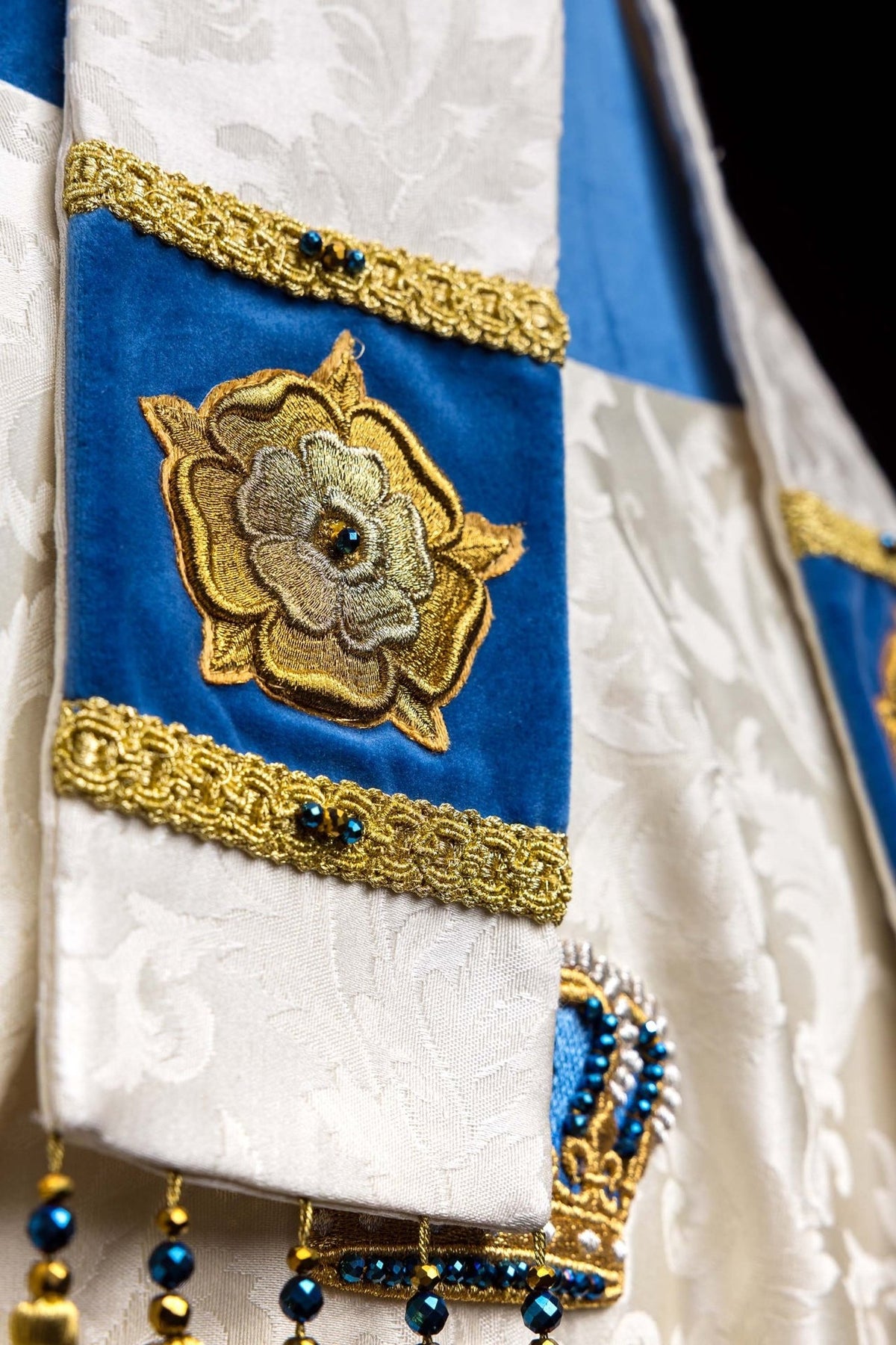 Close-up of Marian miter panel with embroidered gold flower on blue velvet