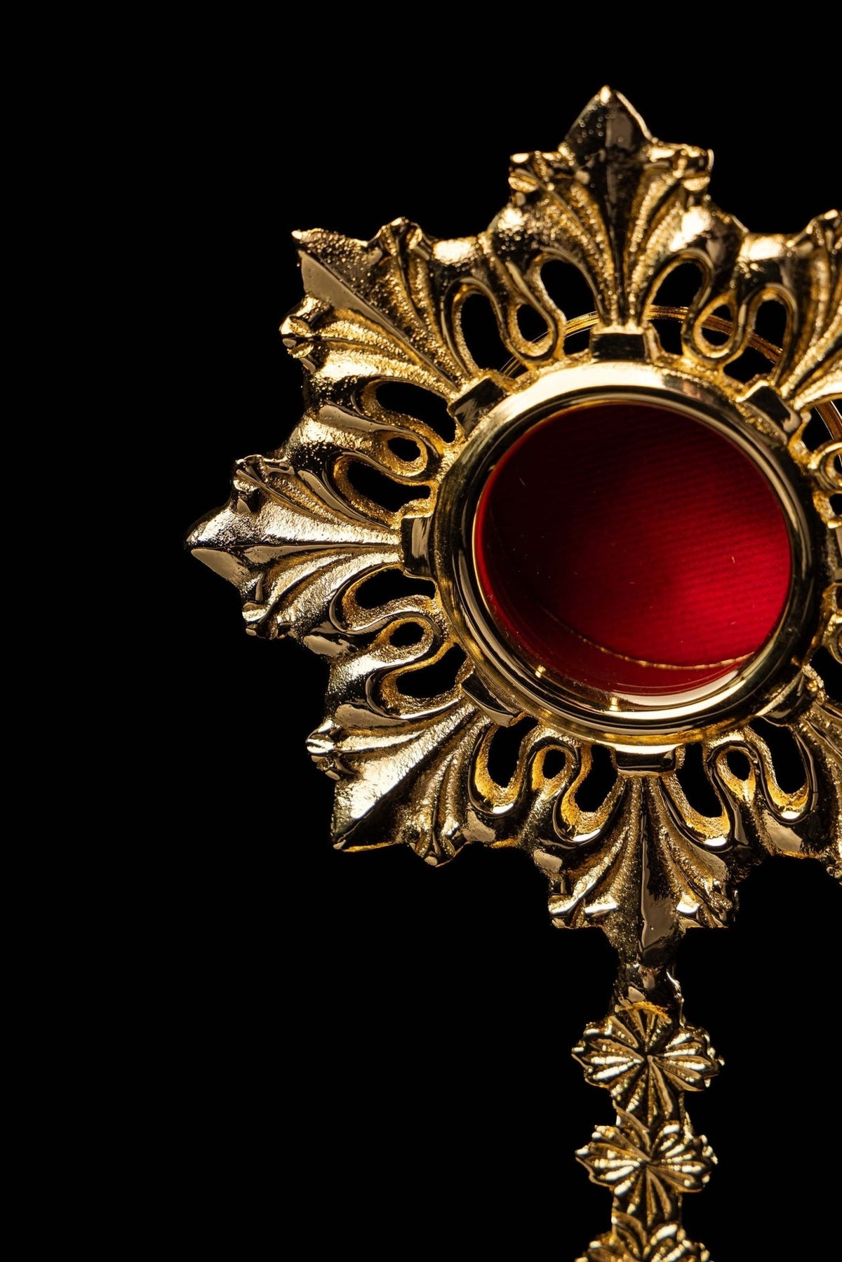 Brass reliquary close-up showing red center and ornate sun-and-rays frame