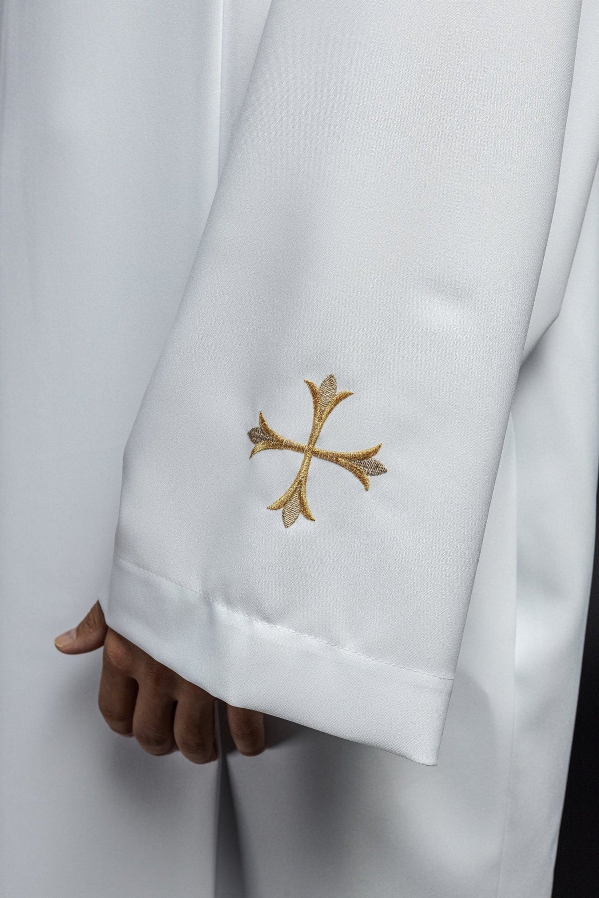 White alb sleeve close-up with embroidered gold cross and finished cuff