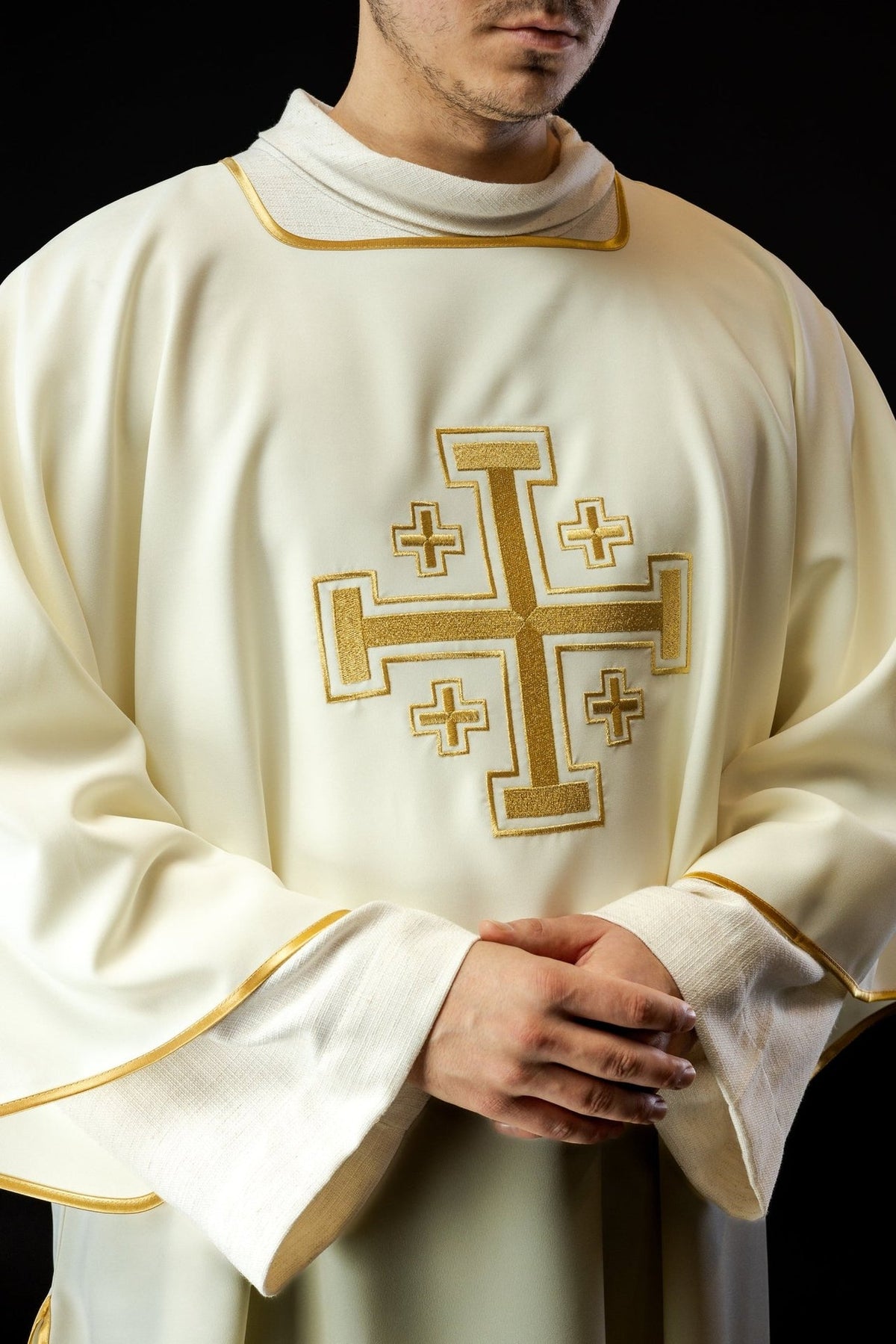 Ecru dalmatic close-up showing embroidered gold cross and gold trim