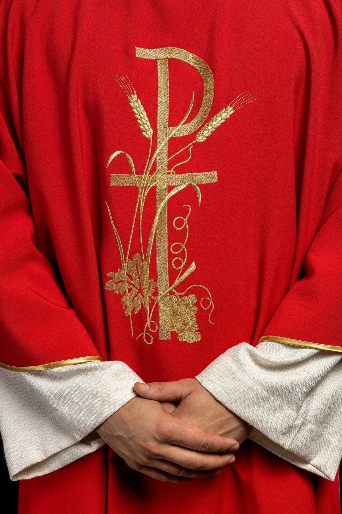 Red dalmatic close-up of gold Pax cross, wheat, grape and vine embroidery