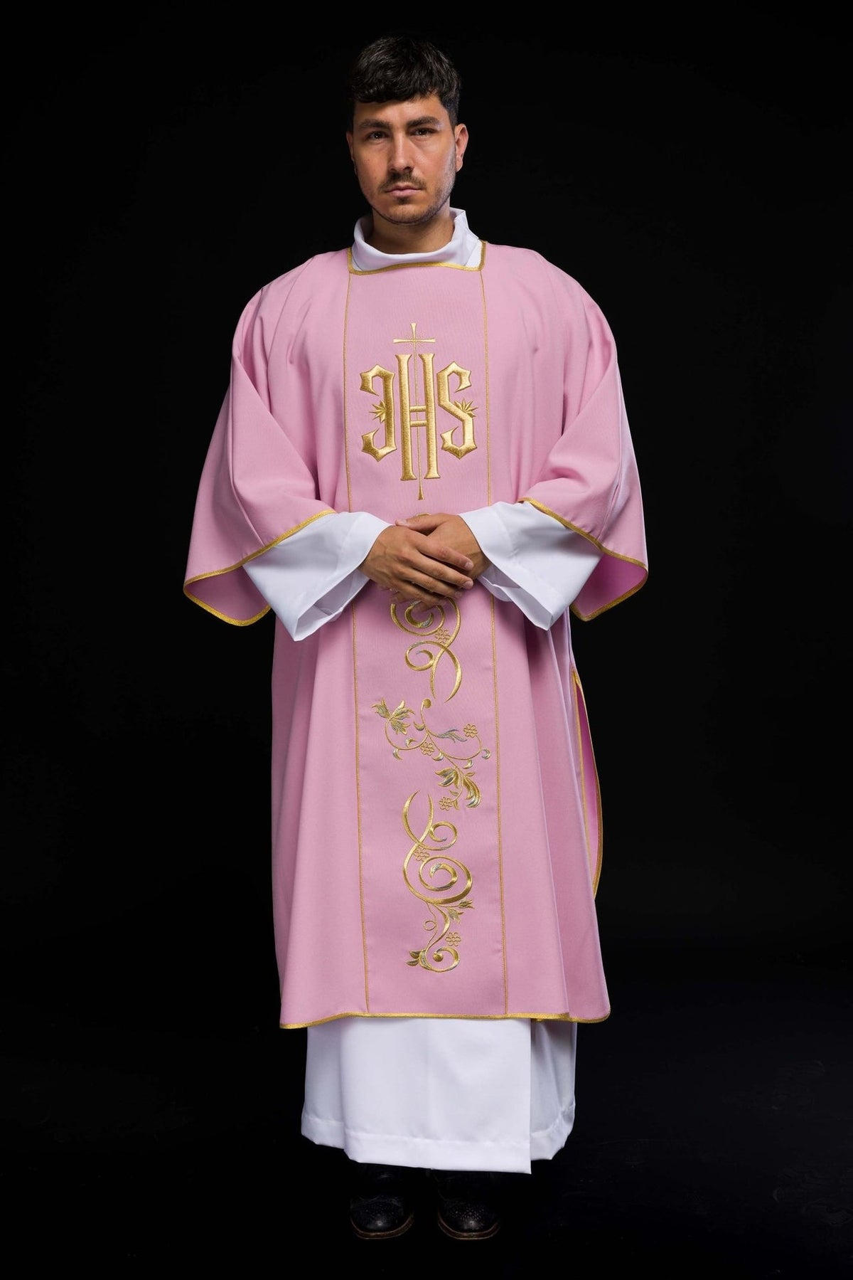 Rose dalmatic worn in front view with gold IHS embroidery and floral orphrey
