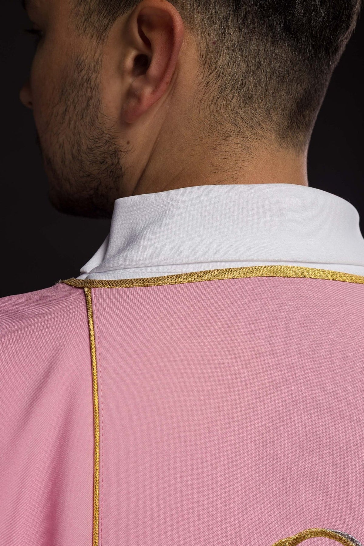 Rose dalmatic back close-up with gold trim and white collar