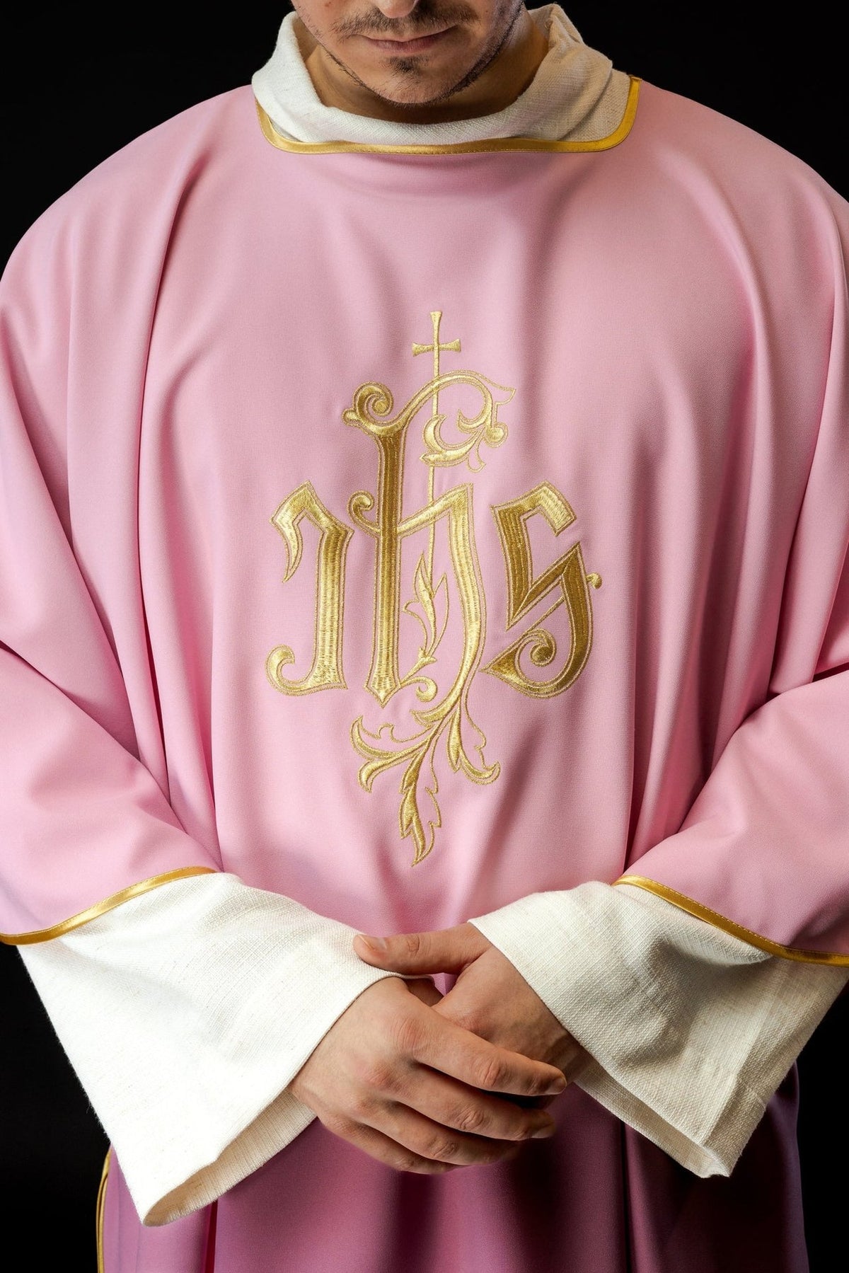 Rose dalmatic close-up with gold IHS embroidery and gold-trimmed neckline