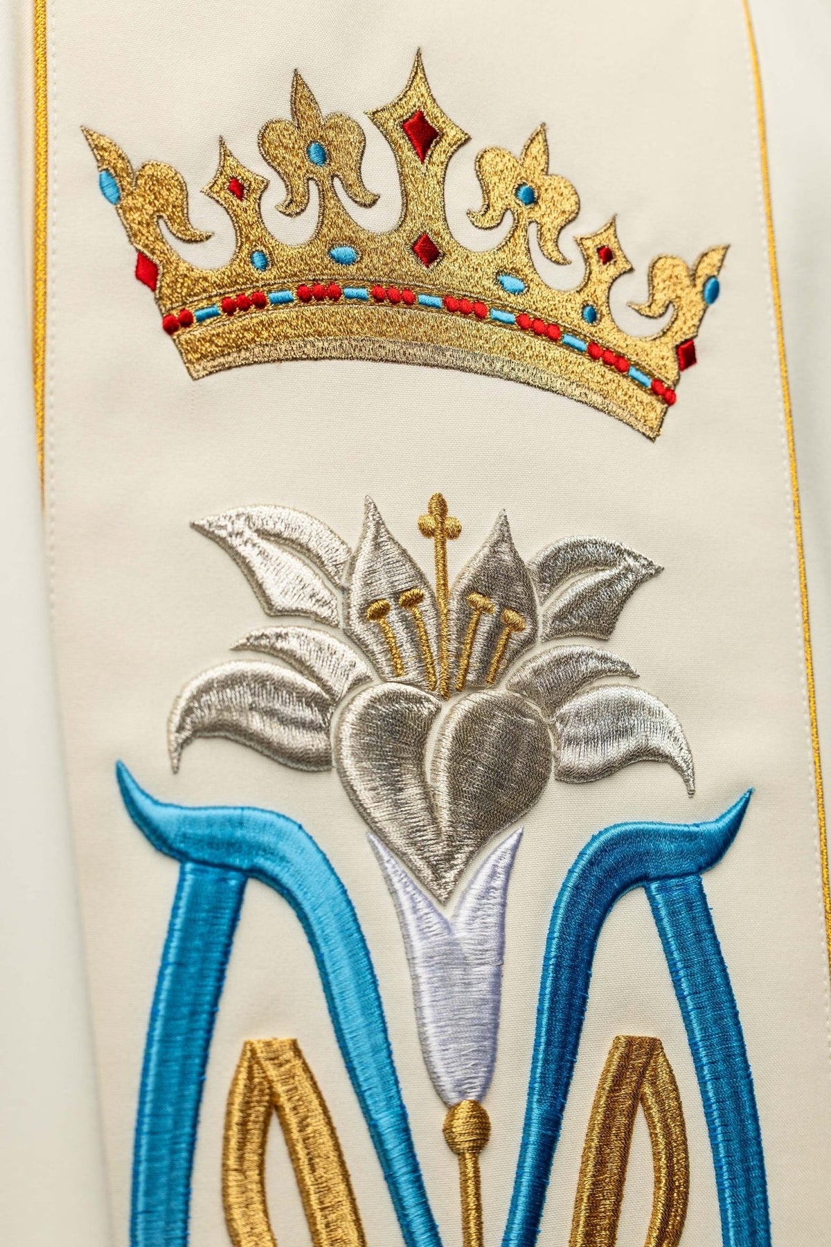 Ecru dalmatic detail showing embroidered gold crown and silver heart with blue Marian symbol
