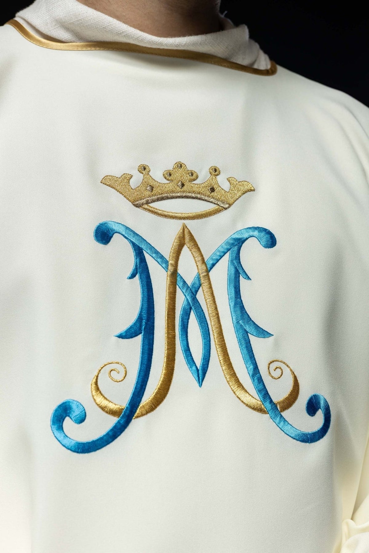 Ecru dalmatic close-up of blue and gold Marian embroidery beneath a crown