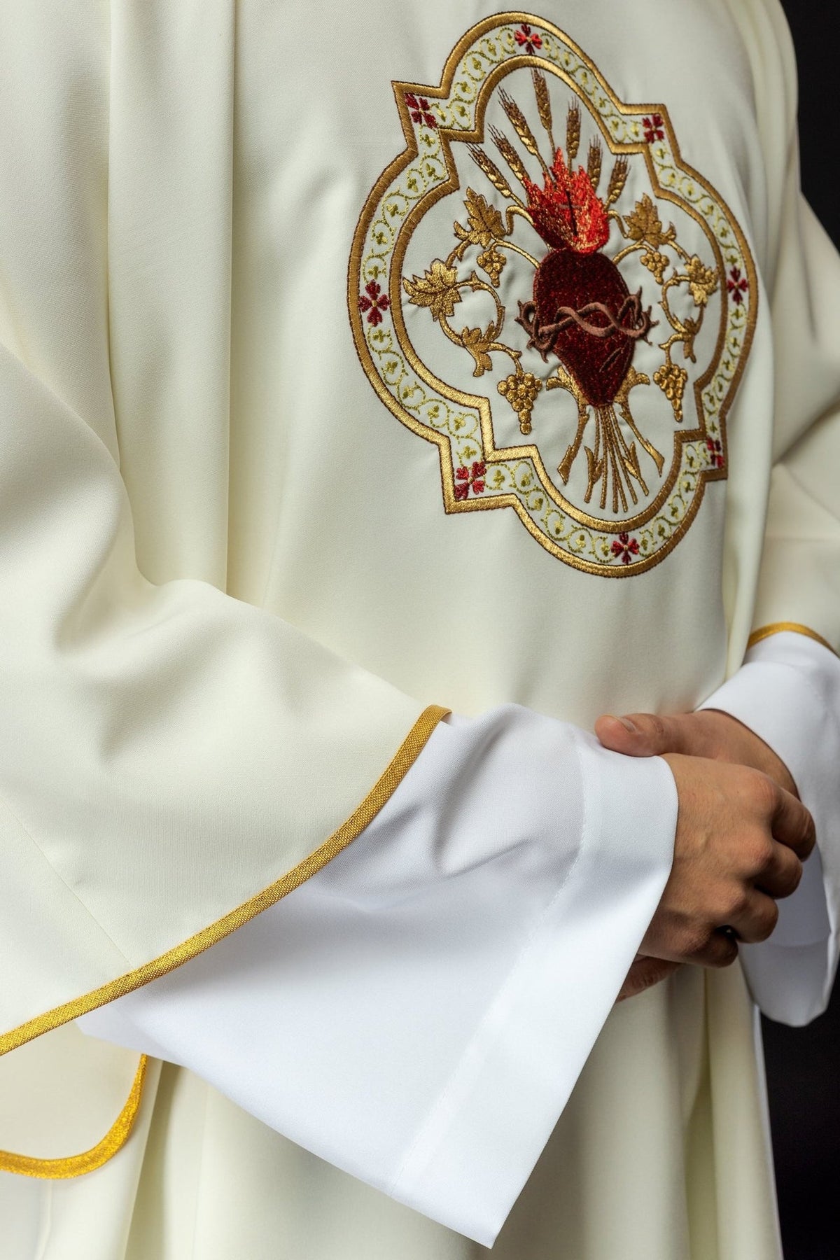 Ecru dalmatic side close-up with Sacred Heart of Jesus embroidery and gold sleeve trim