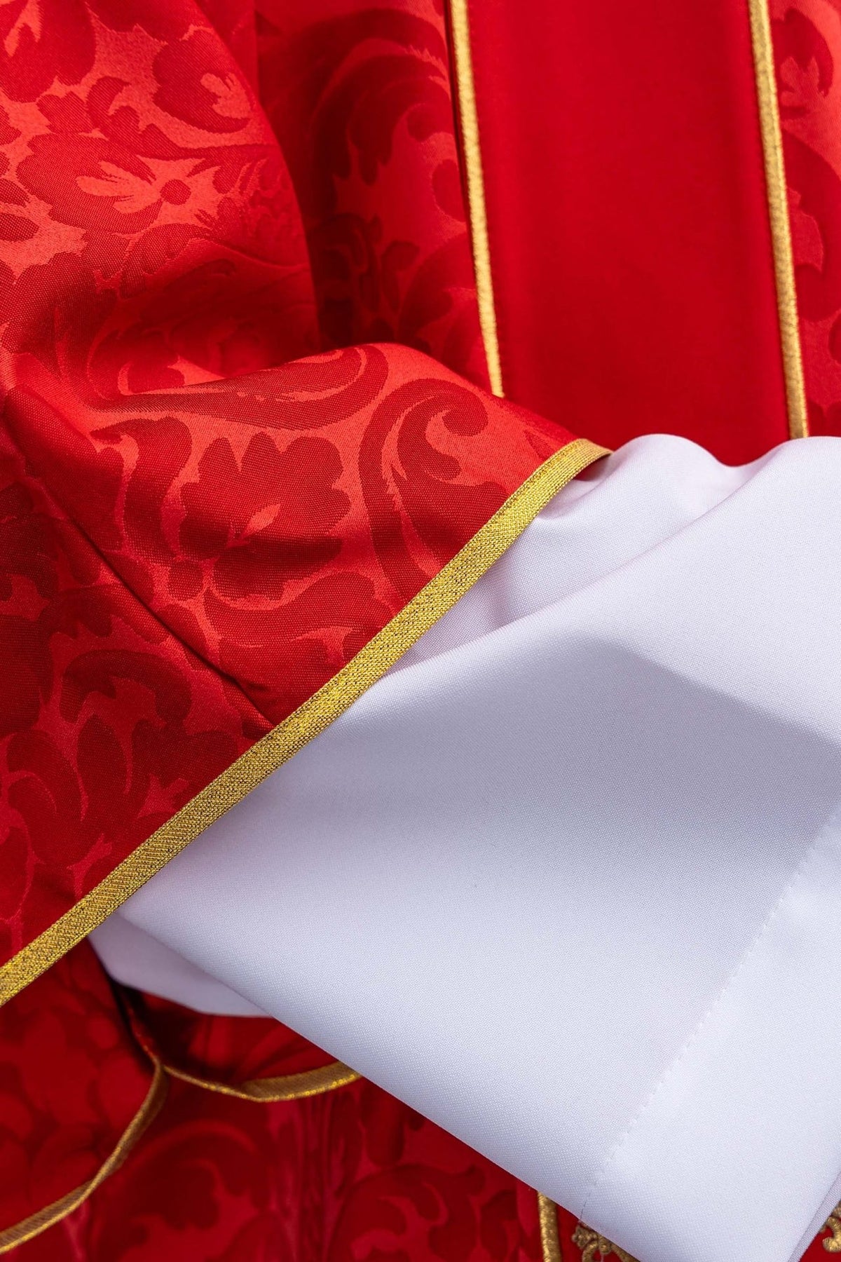 Red dalmatic close-up showing red jacquard fabric and gold trim at the sleeve