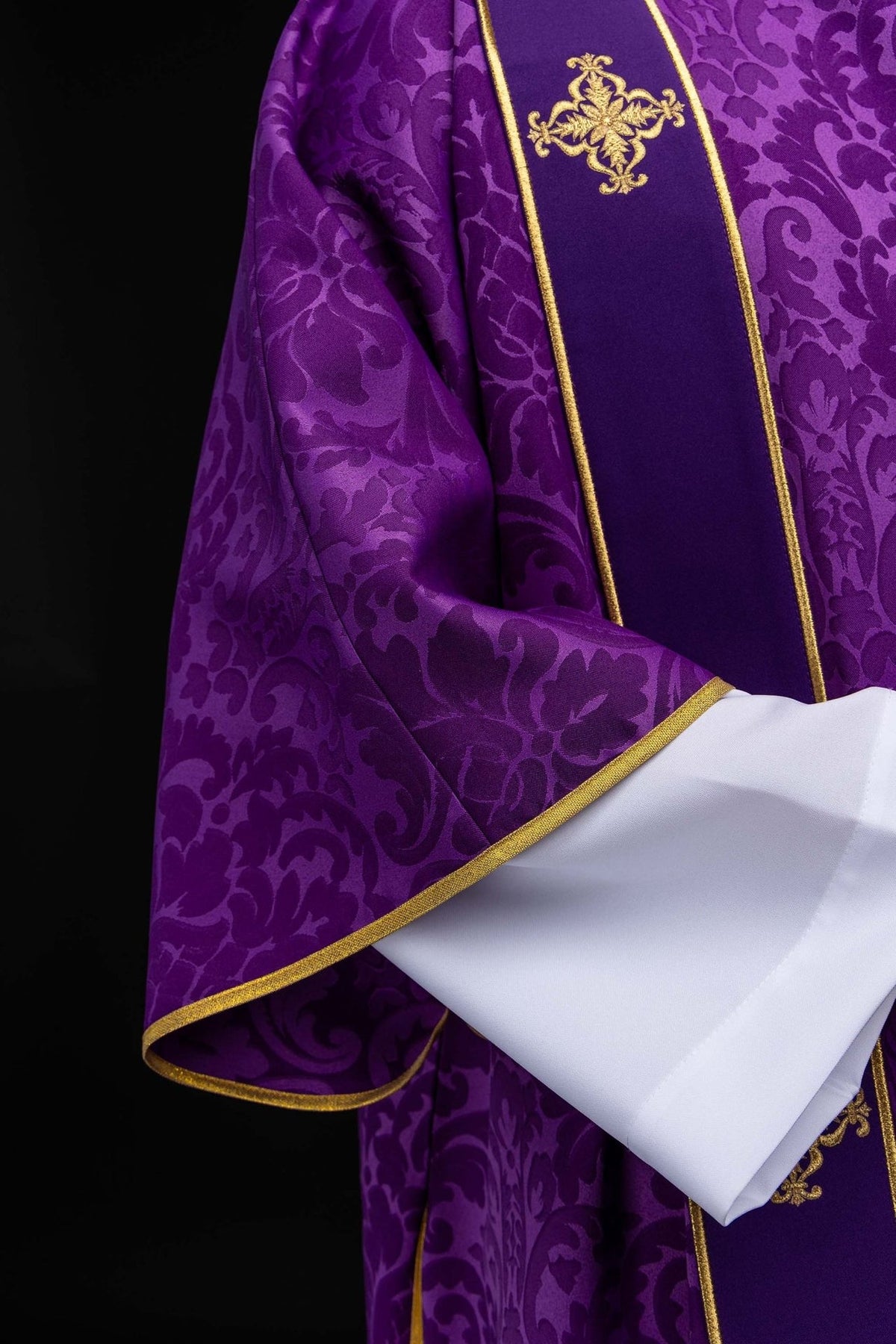 Purple dalmatic close-up showing gold trim and embroidered cross