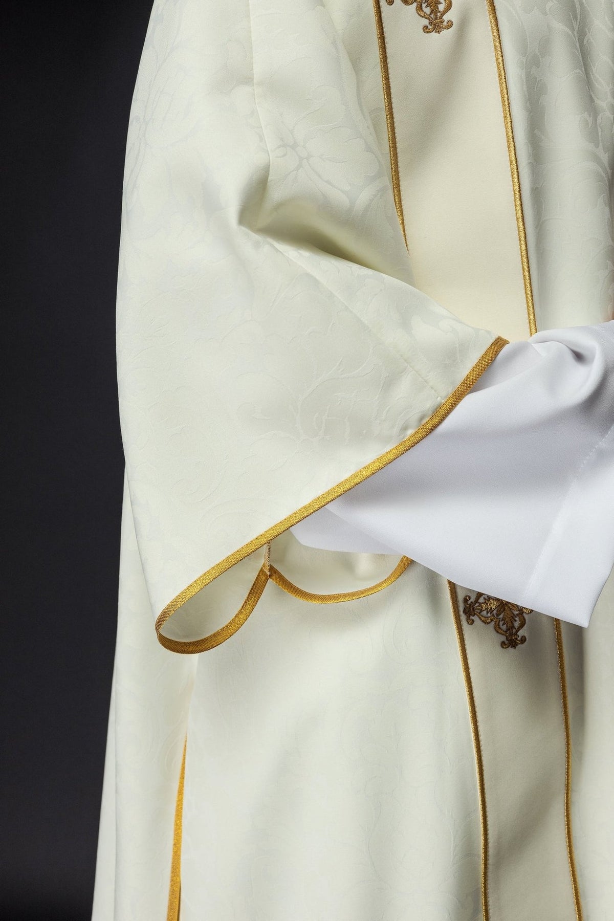 Ecru dalmatic sleeve close-up with jacquard fabric and gold trim