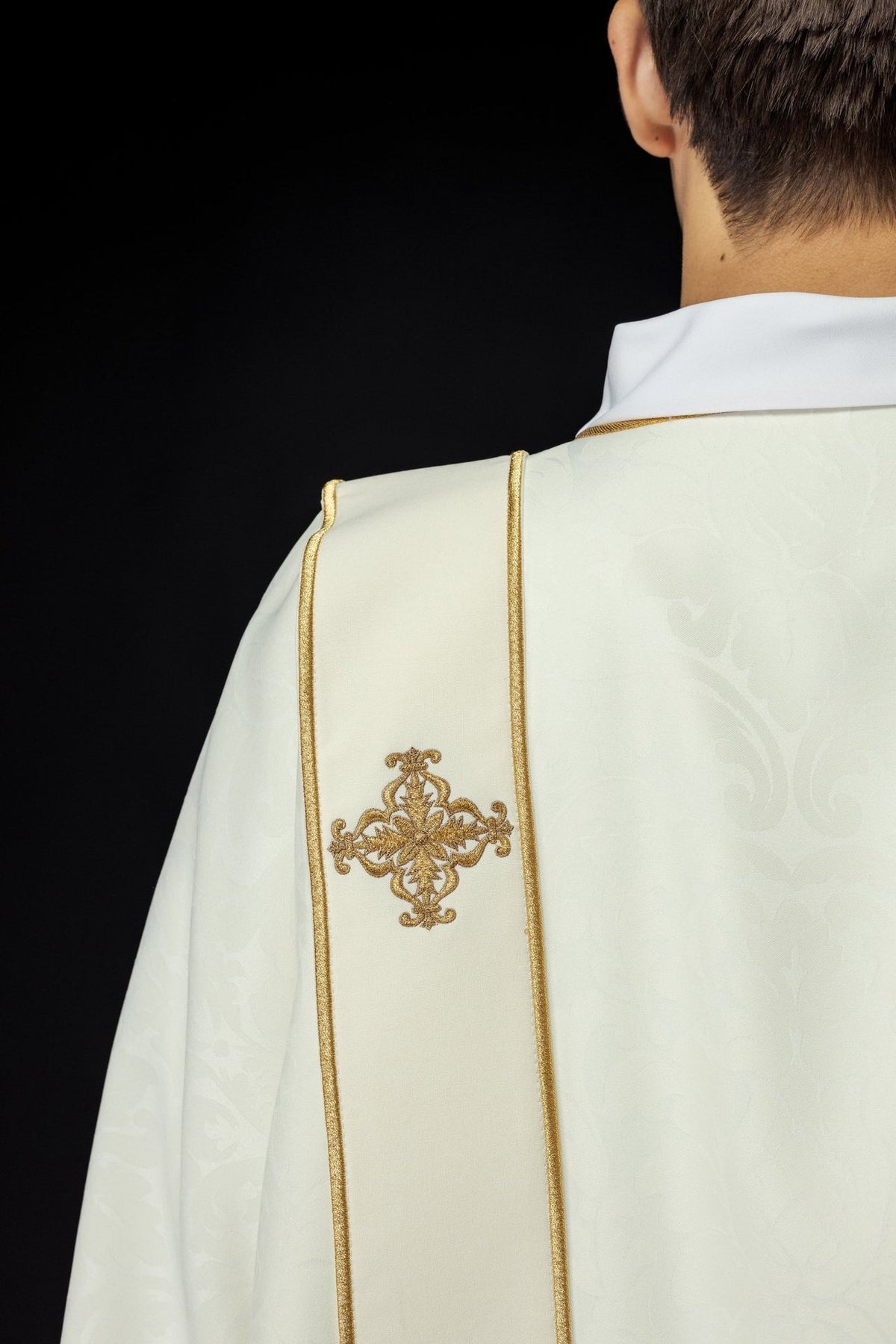 Ecru dalmatic back close-up with gold-trimmed orphrey and embroidered cross