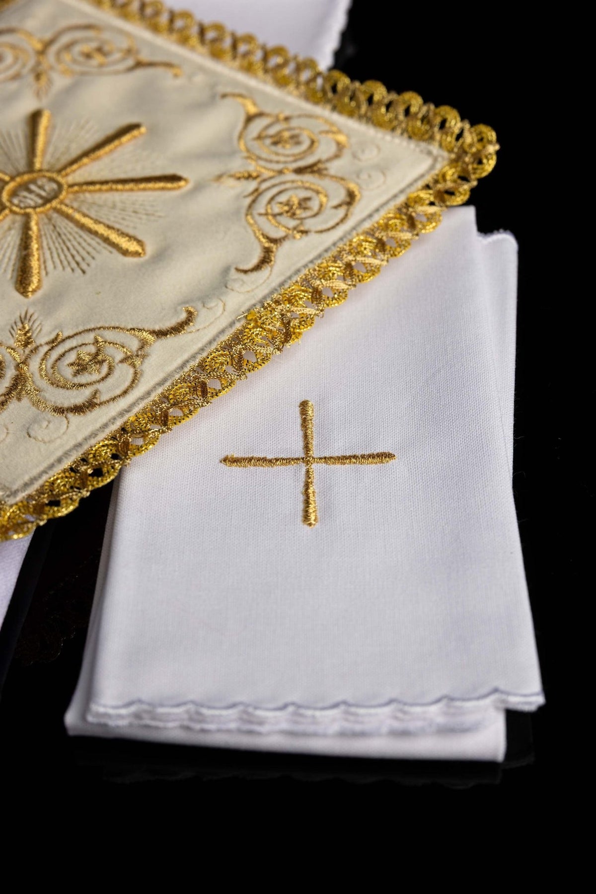 Altar linen set detail showing gold cross embroidery on folded white linen with scalloped edges