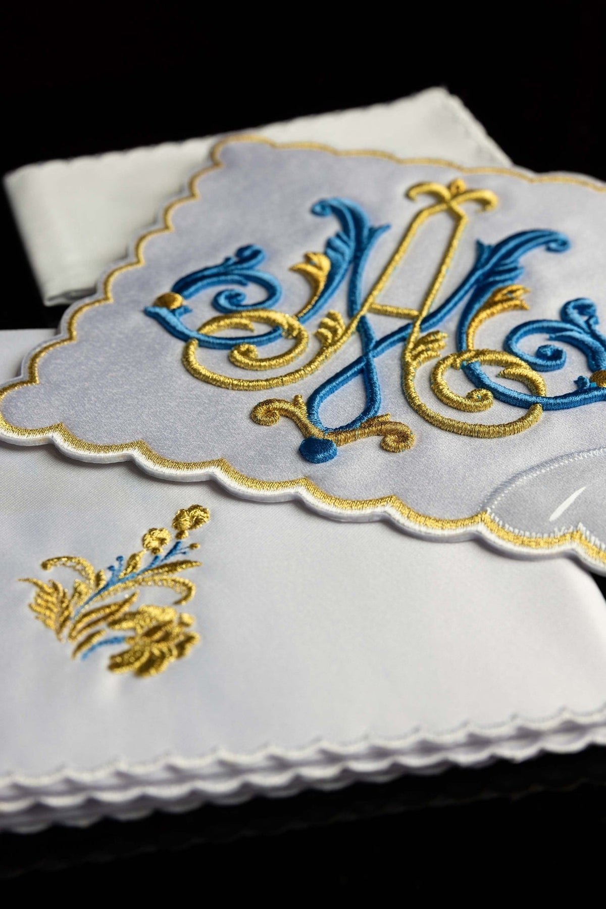 Altar linen set detail showing embroidered blue and gold Marian motif on white fabric