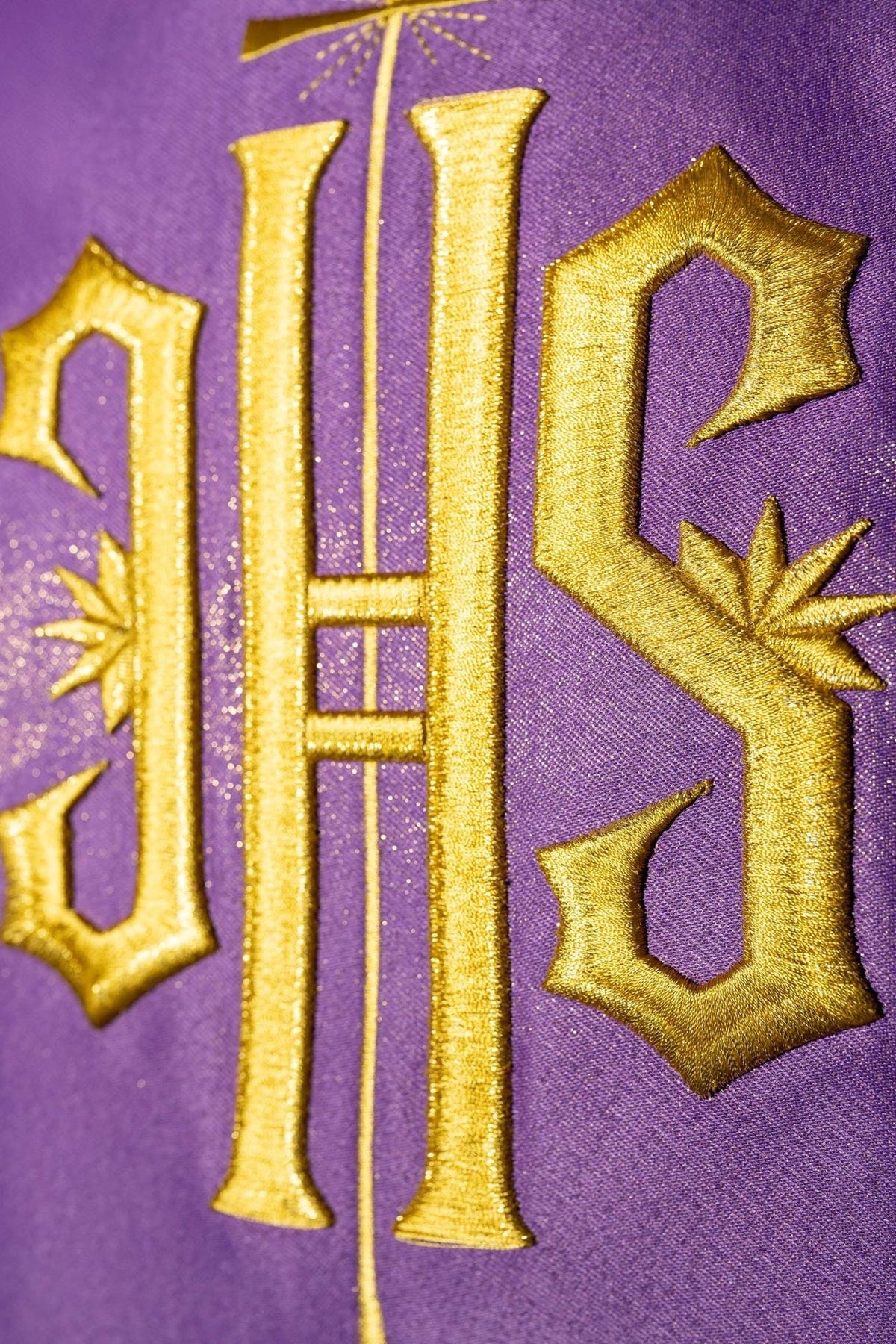 Purple chasuble close-up showing gold embroidered IHS motif